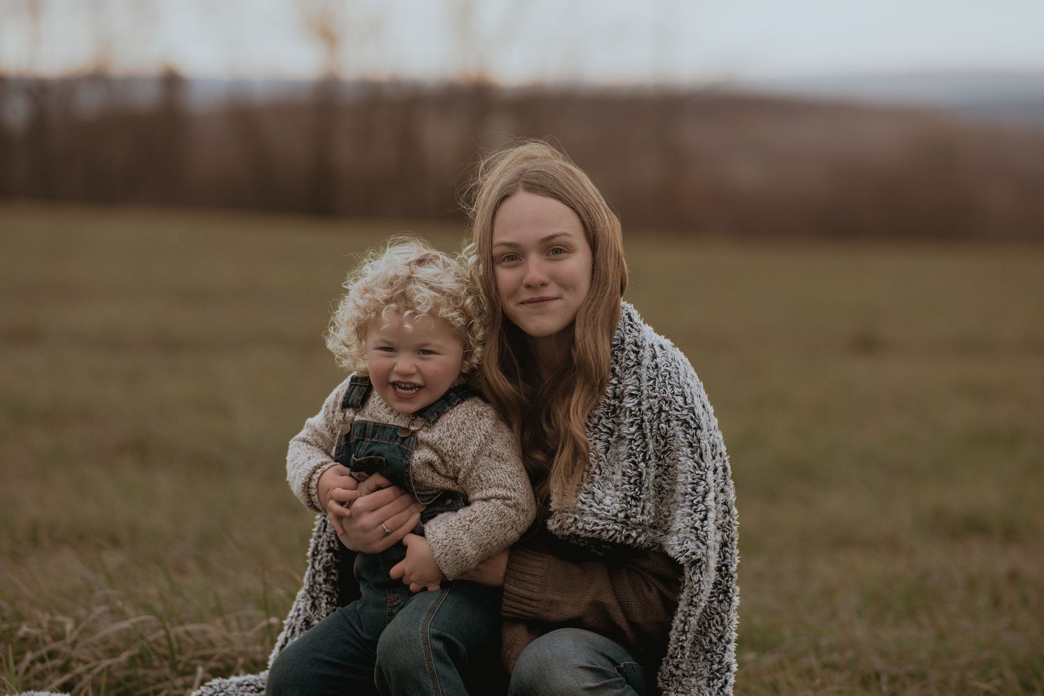 Sweet candid interaction between parent and child in an autumn field setting.