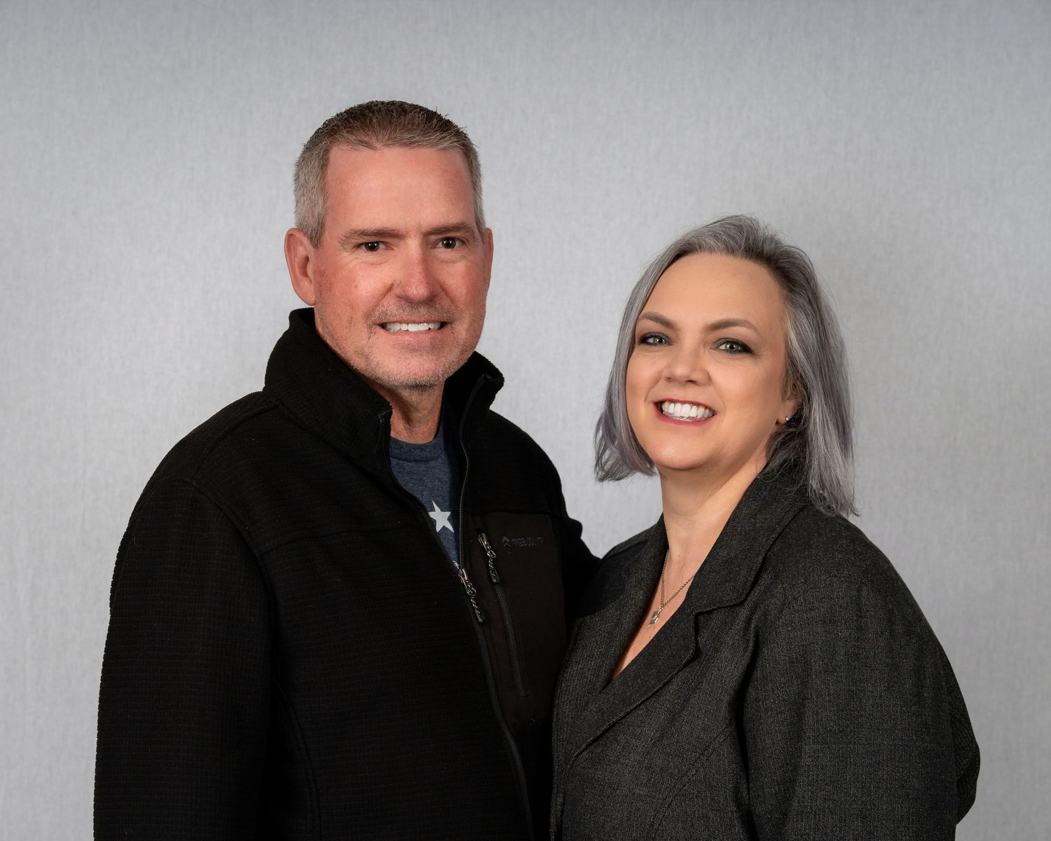 Professional studio portrait against grey background in business attire.