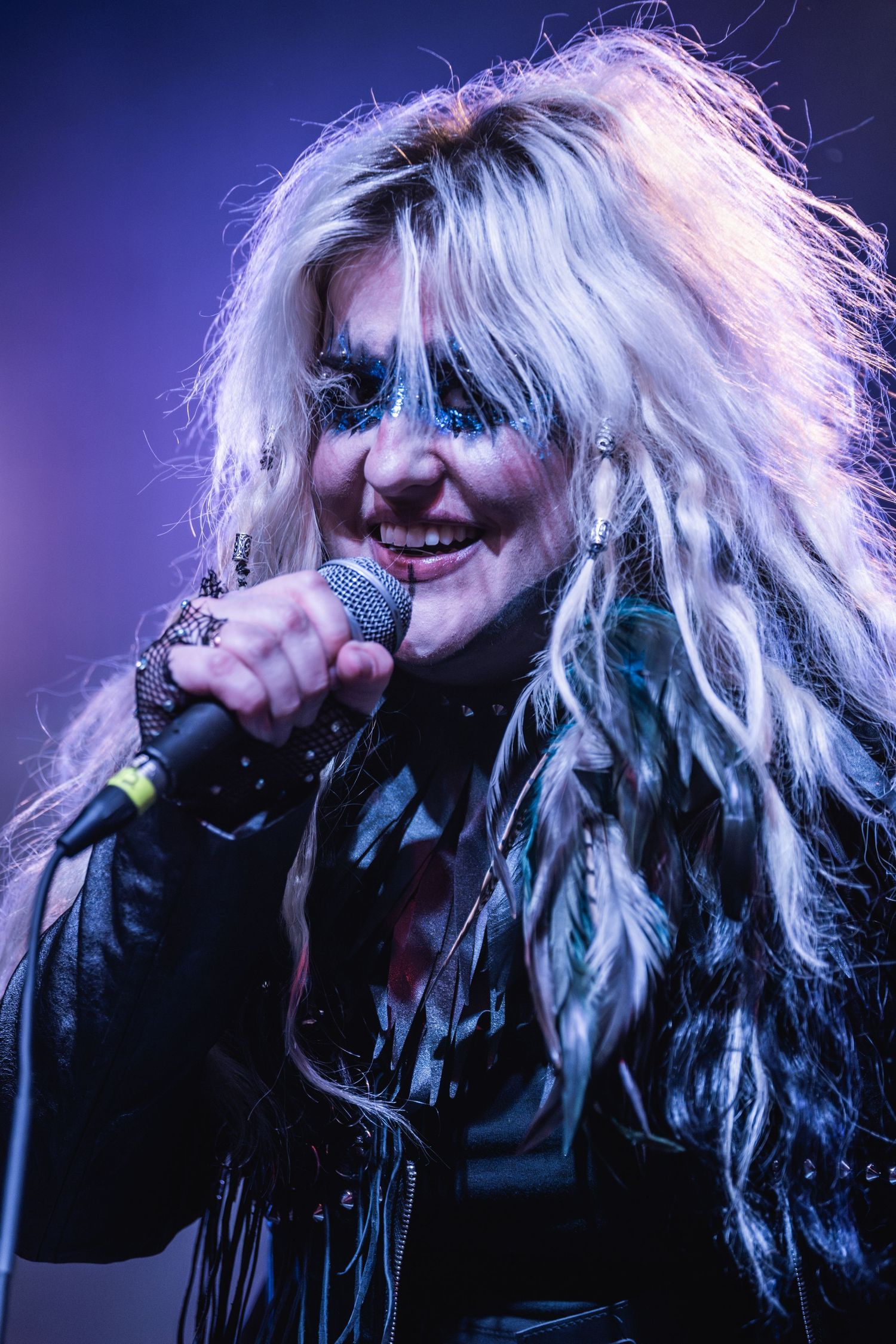 Live concert performance with dramatic lighting and theatrical makeup under purple stage effects.