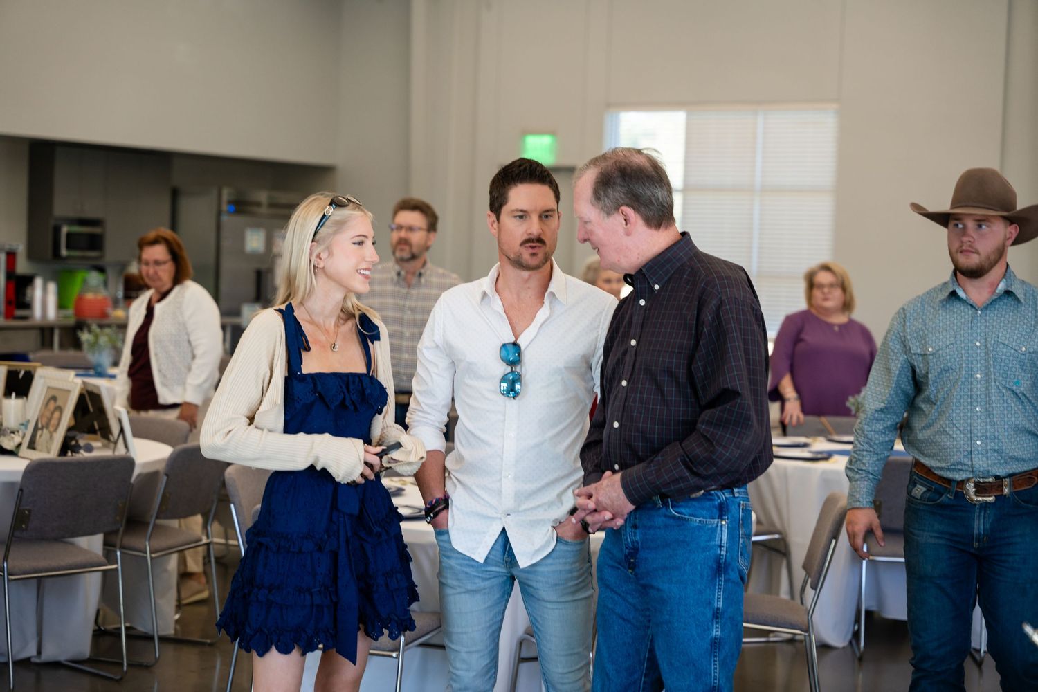 A casual indoor gathering with people socializing in a bright room with folding chairs.