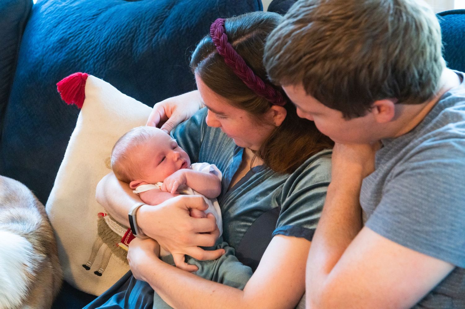 A tender family moment looking down at their newborn baby on a blue couch.