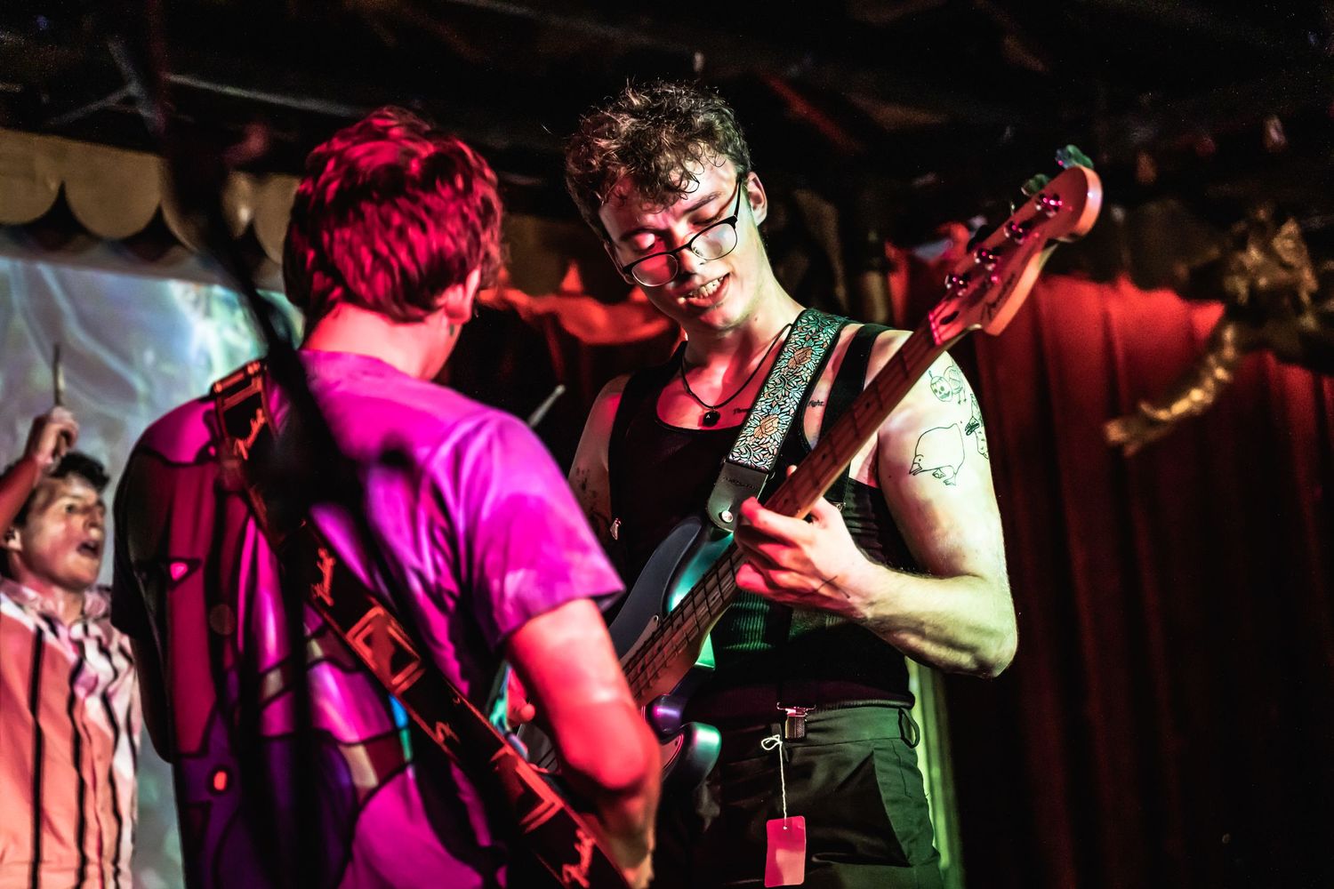 Musicians performing on stage under vibrant red lighting.