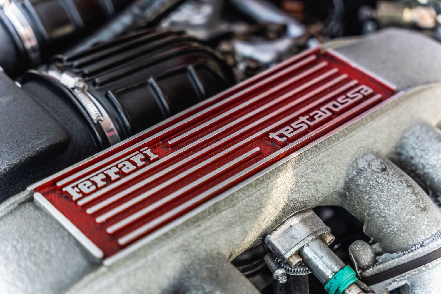 Close-up detail of a red Ferrari engine cover with ribbed design pattern.