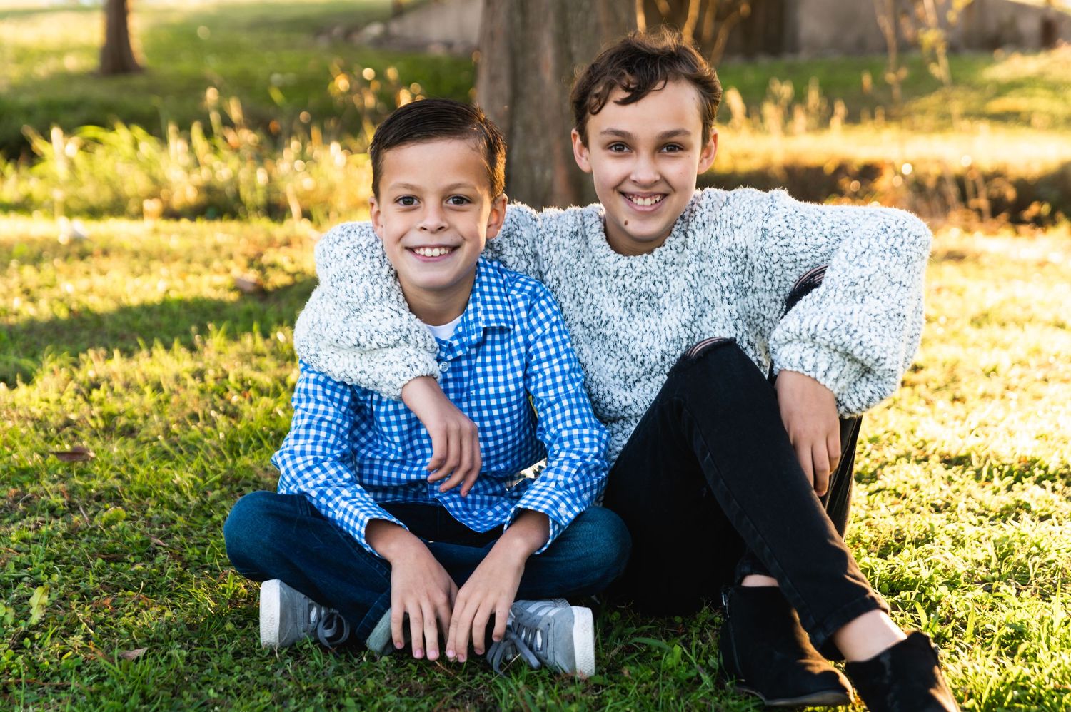 Two people sitting together on grass during golden hour autumn lighting.