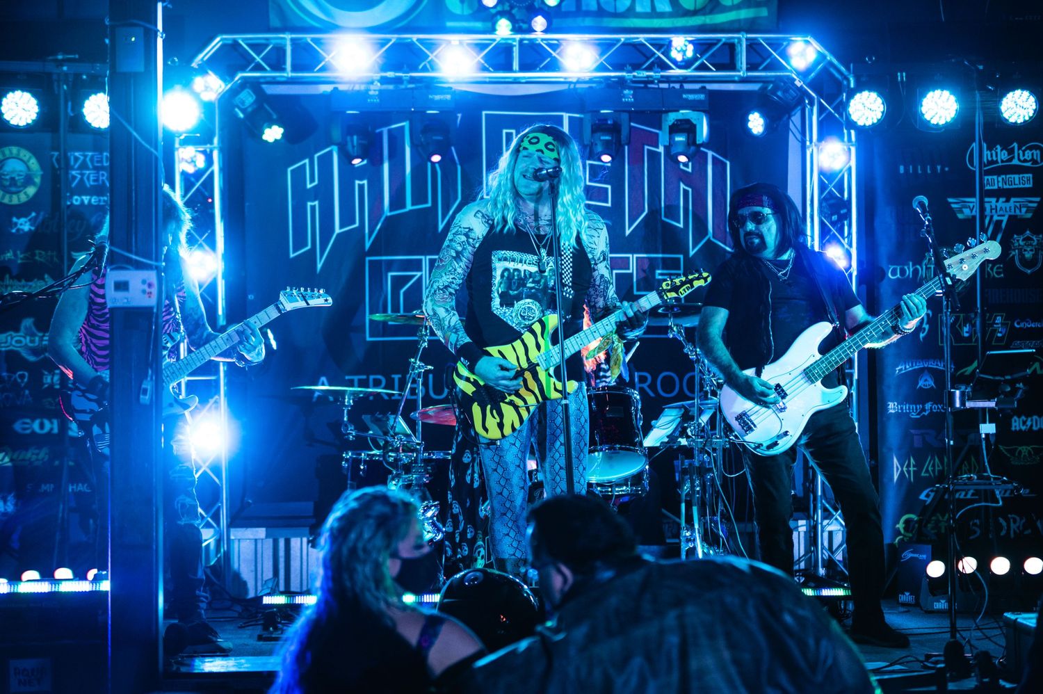 Band playing on stage with bright blue concert lighting and crowd below.