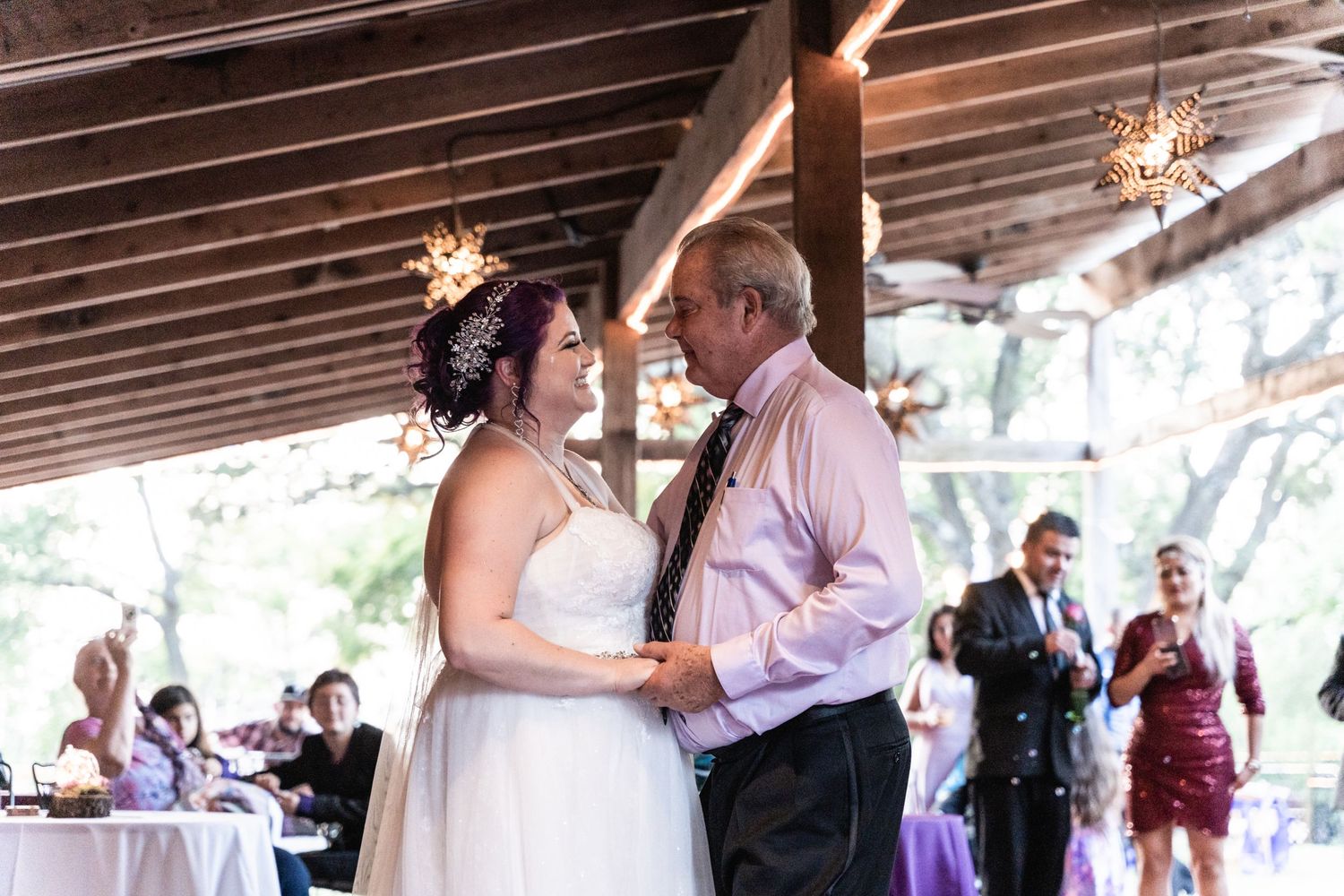 A dance moment under wooden beams at a wedding reception.