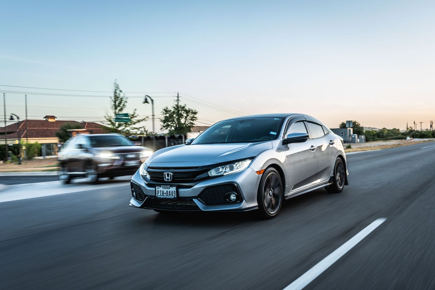 Silver Honda Civic Sport photographed during a dynamic drive at sunset.