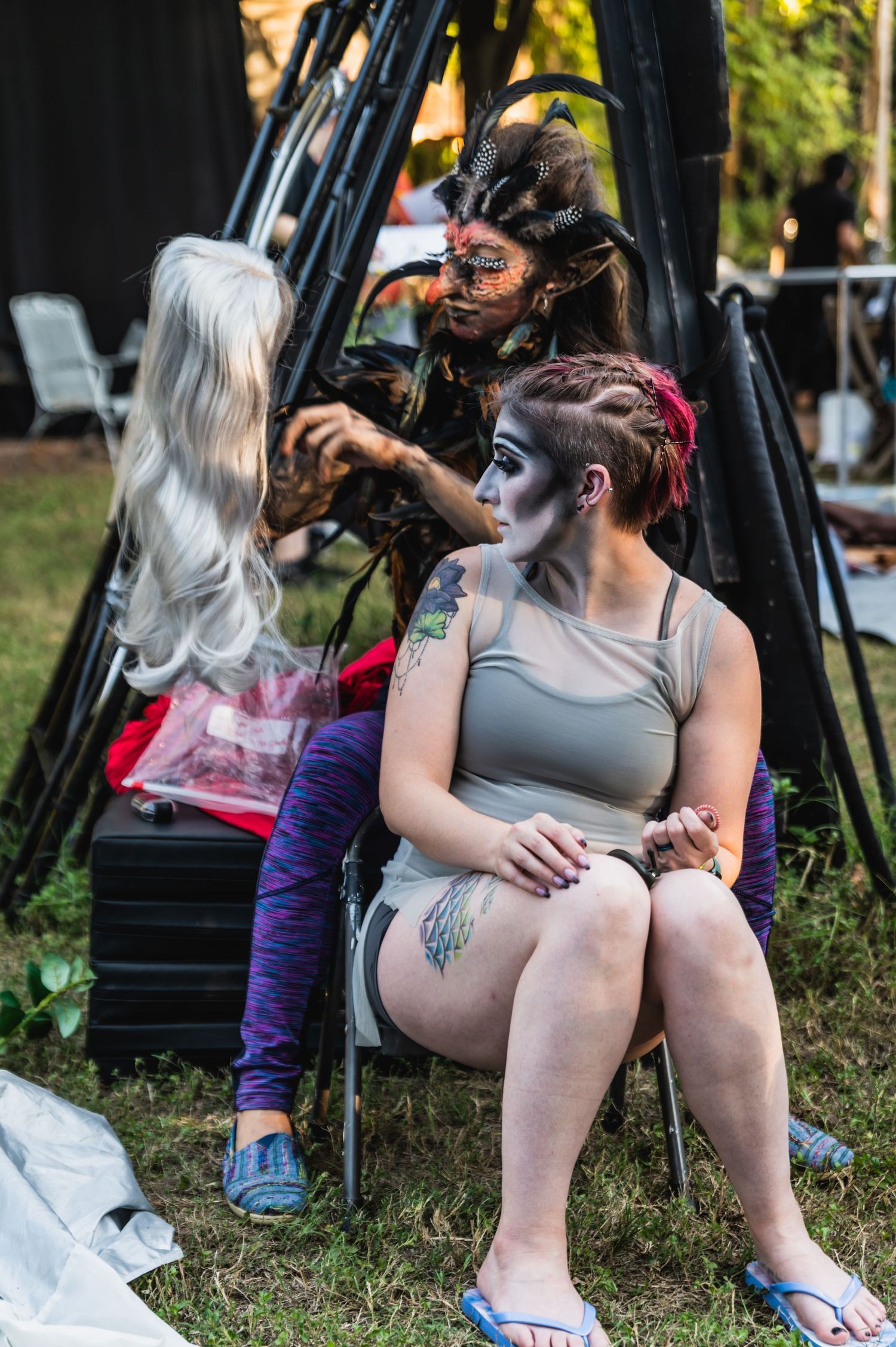 Behind the scenes of theatrical makeup application and costume preparation outdoors.