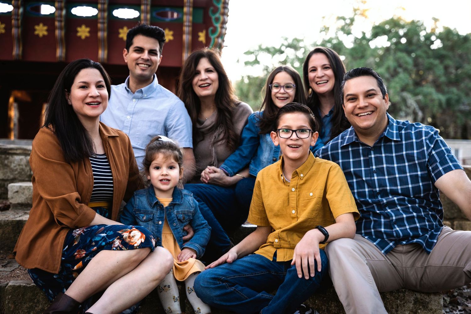 Multi-generational family group sitting together outdoors for casual portrait.