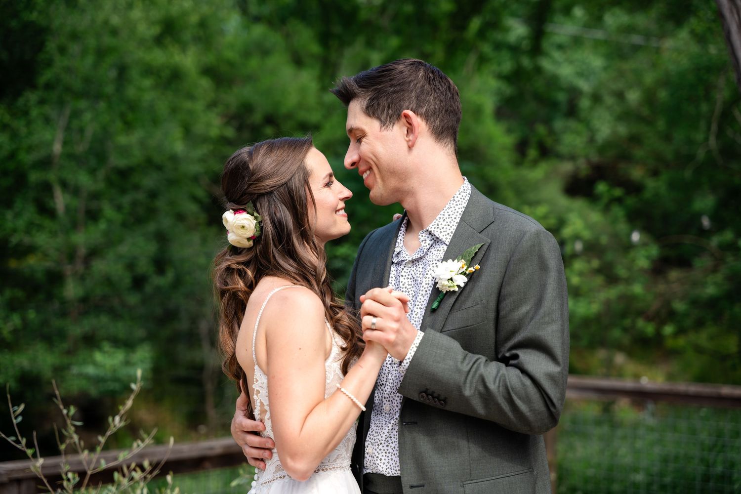 A romantic outdoor moment between newlyweds against a lush green background.