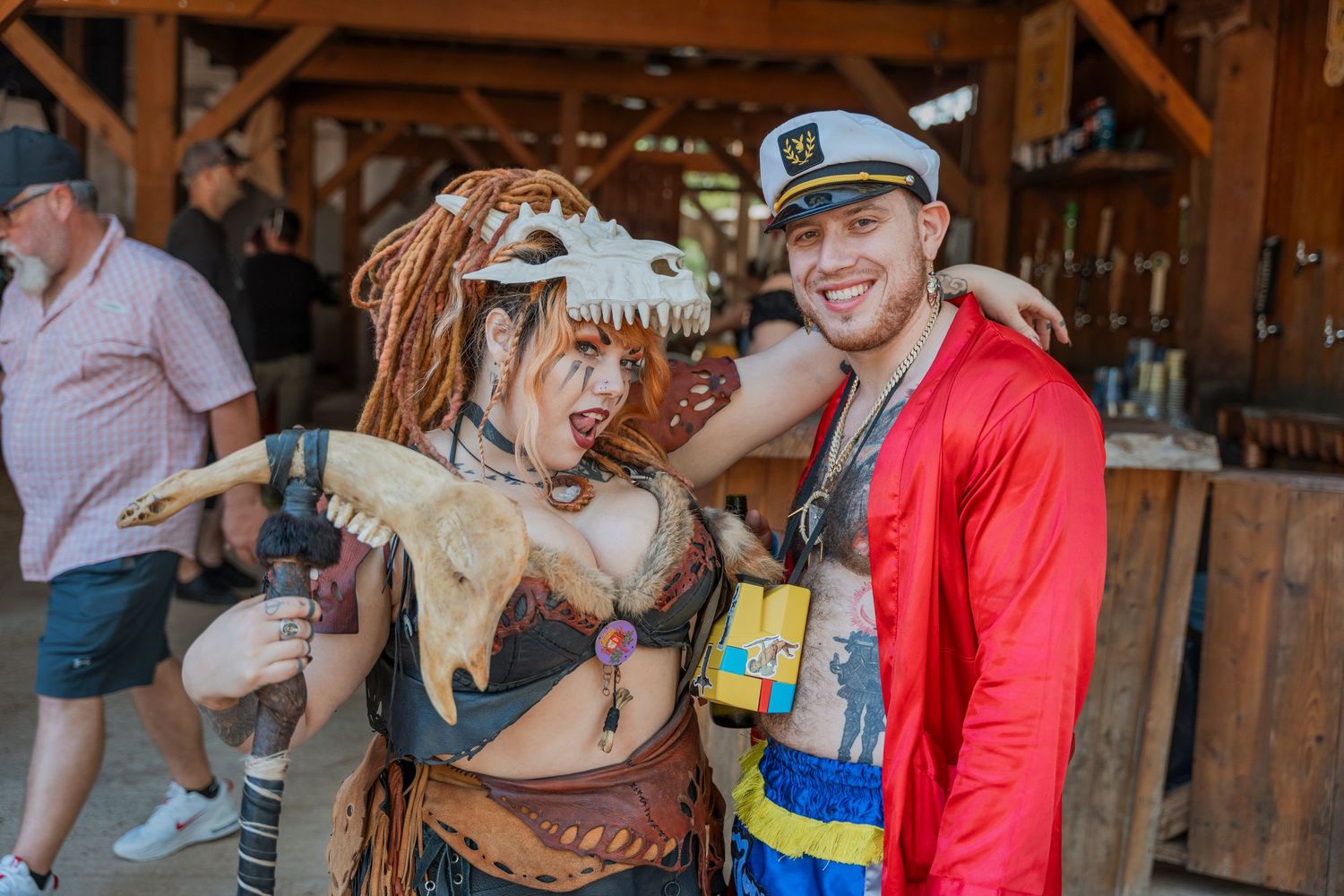 Two people in creative steampunk and nautical costumes pose together at a festival.