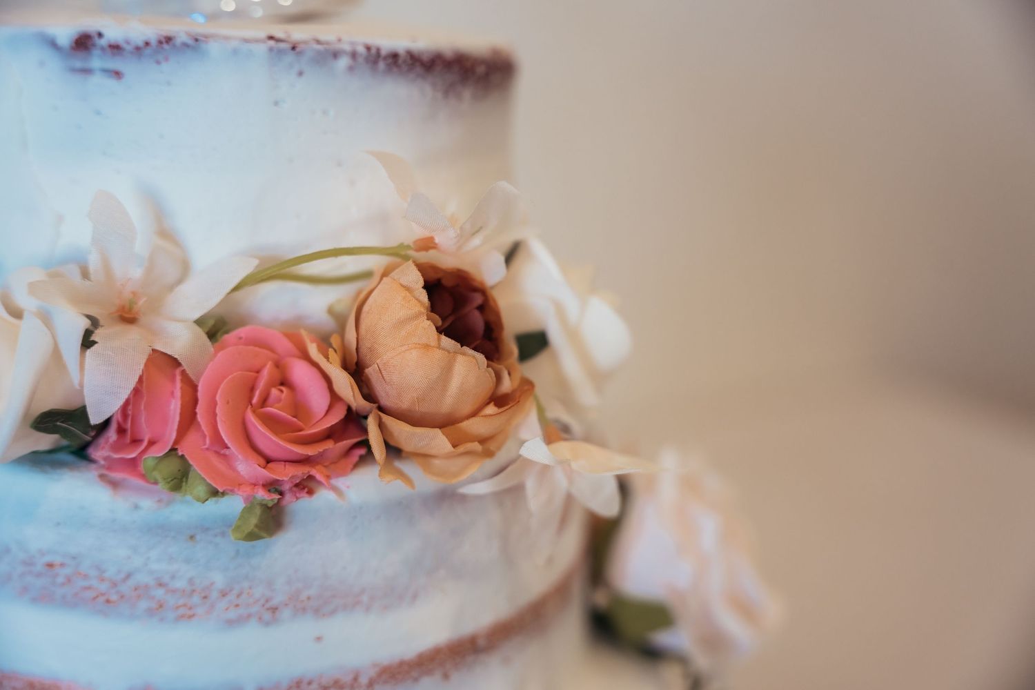 Close-up detail of delicate floral decorations on a semi-naked wedding cake.