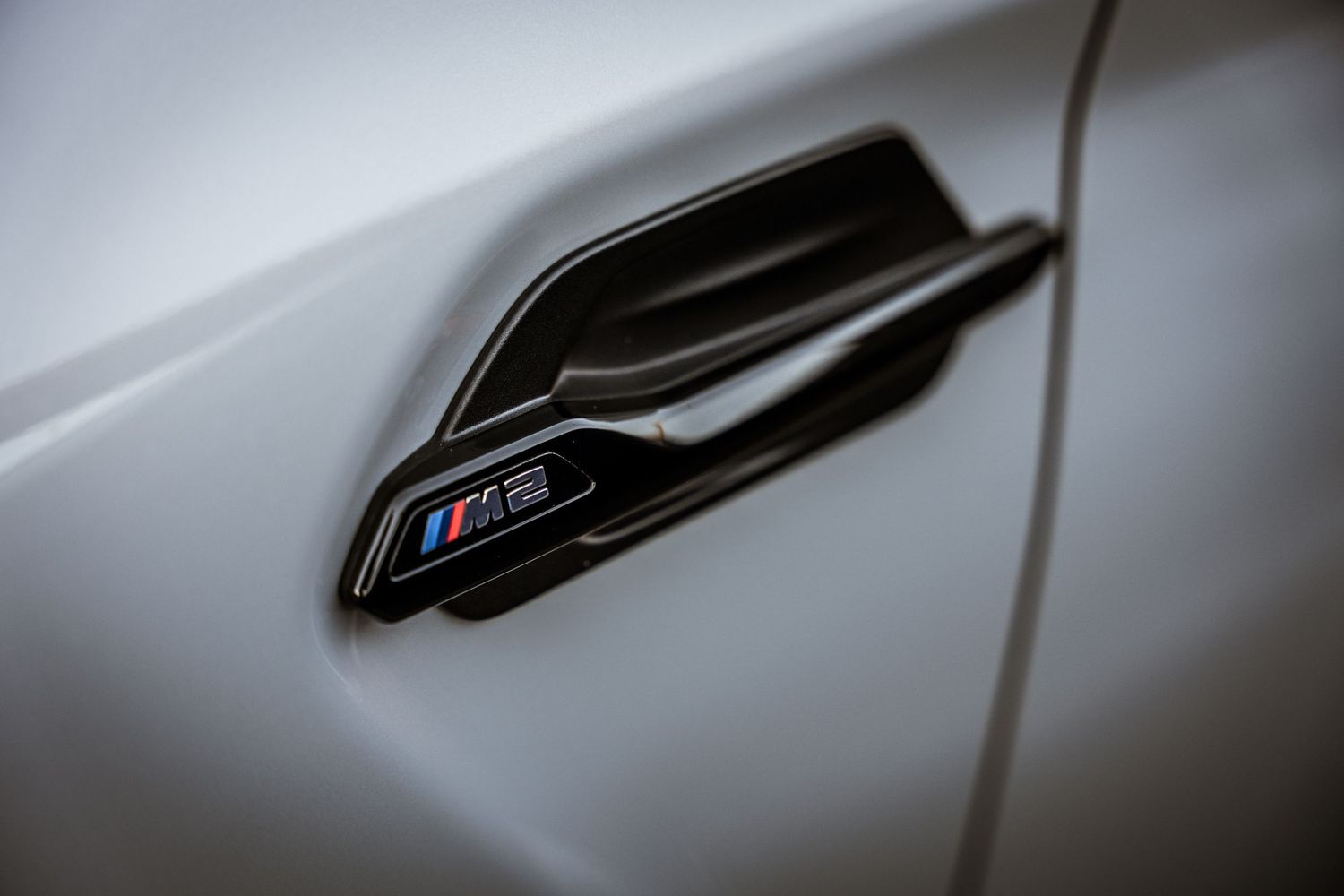 Close-up detail of a BMW M-series side fender badge in black and chrome.
