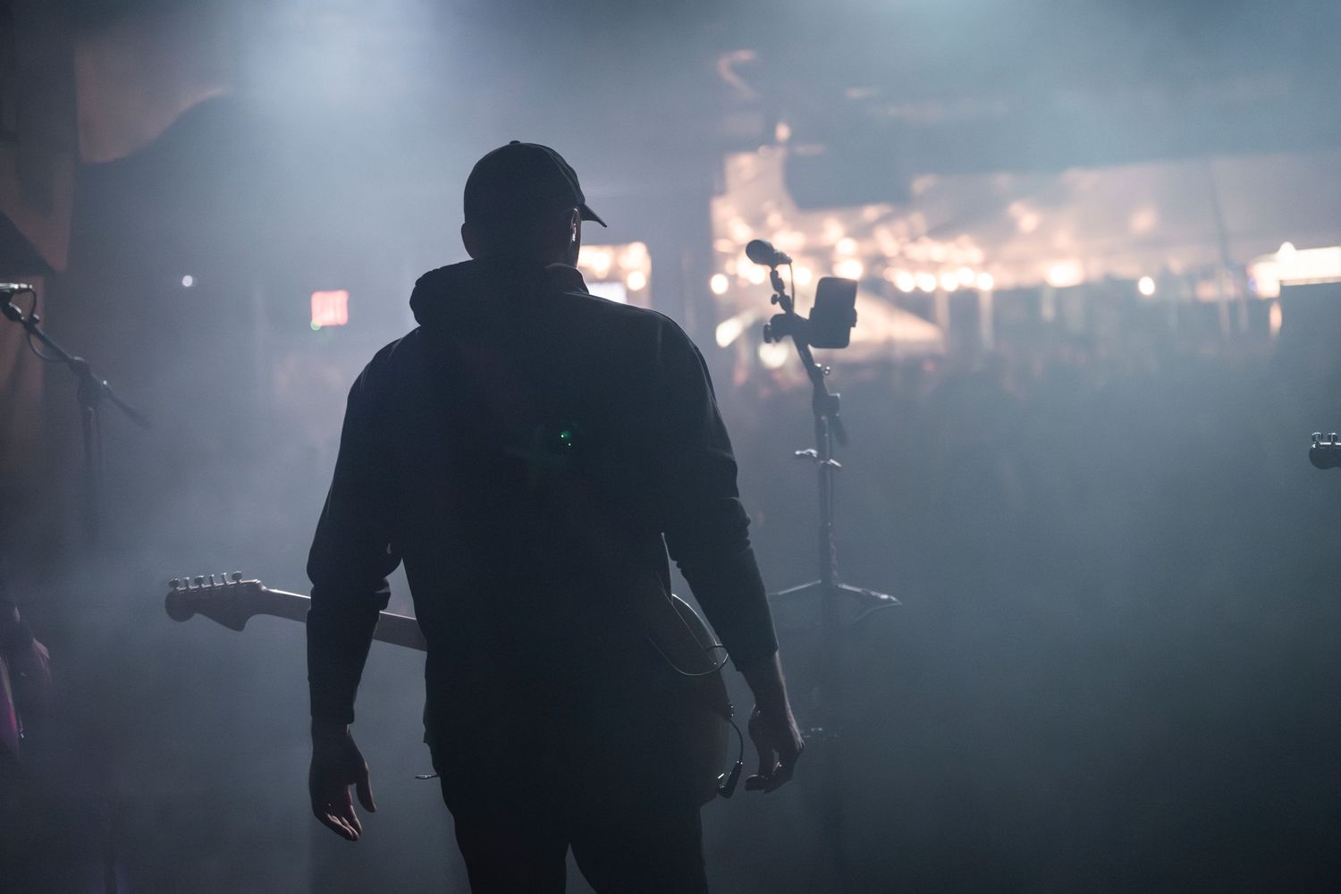 Silhouette of musician performing on stage amidst atmospheric fog and lighting effects.