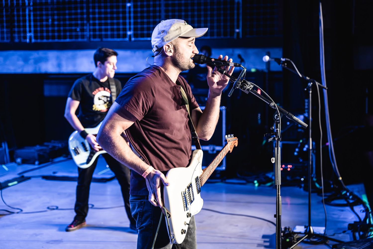 Band performing live on stage with blue lighting and musical instruments.
