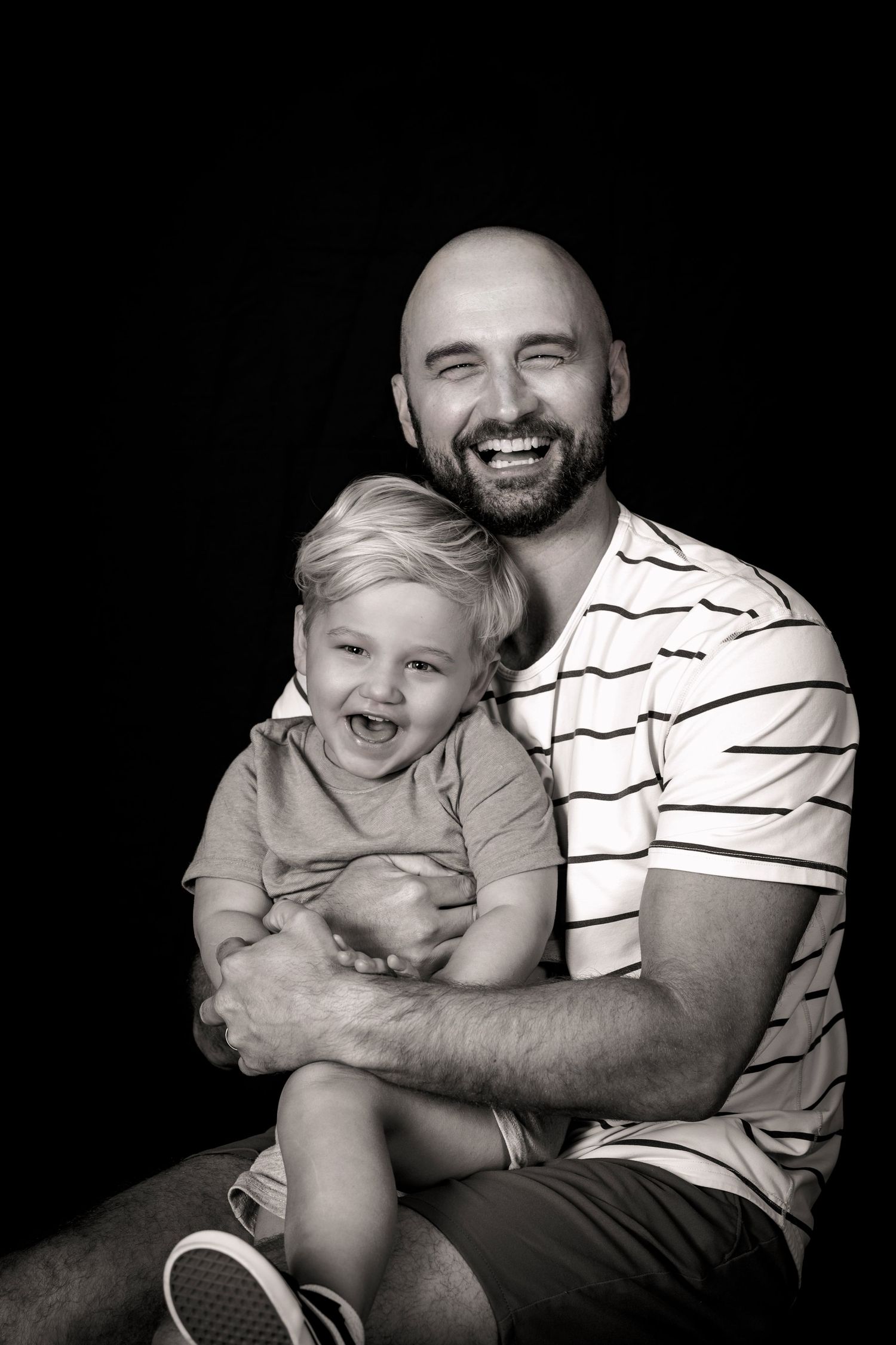 Black and white portrait of cheerful parent and child in striped shirt sharing laughter.