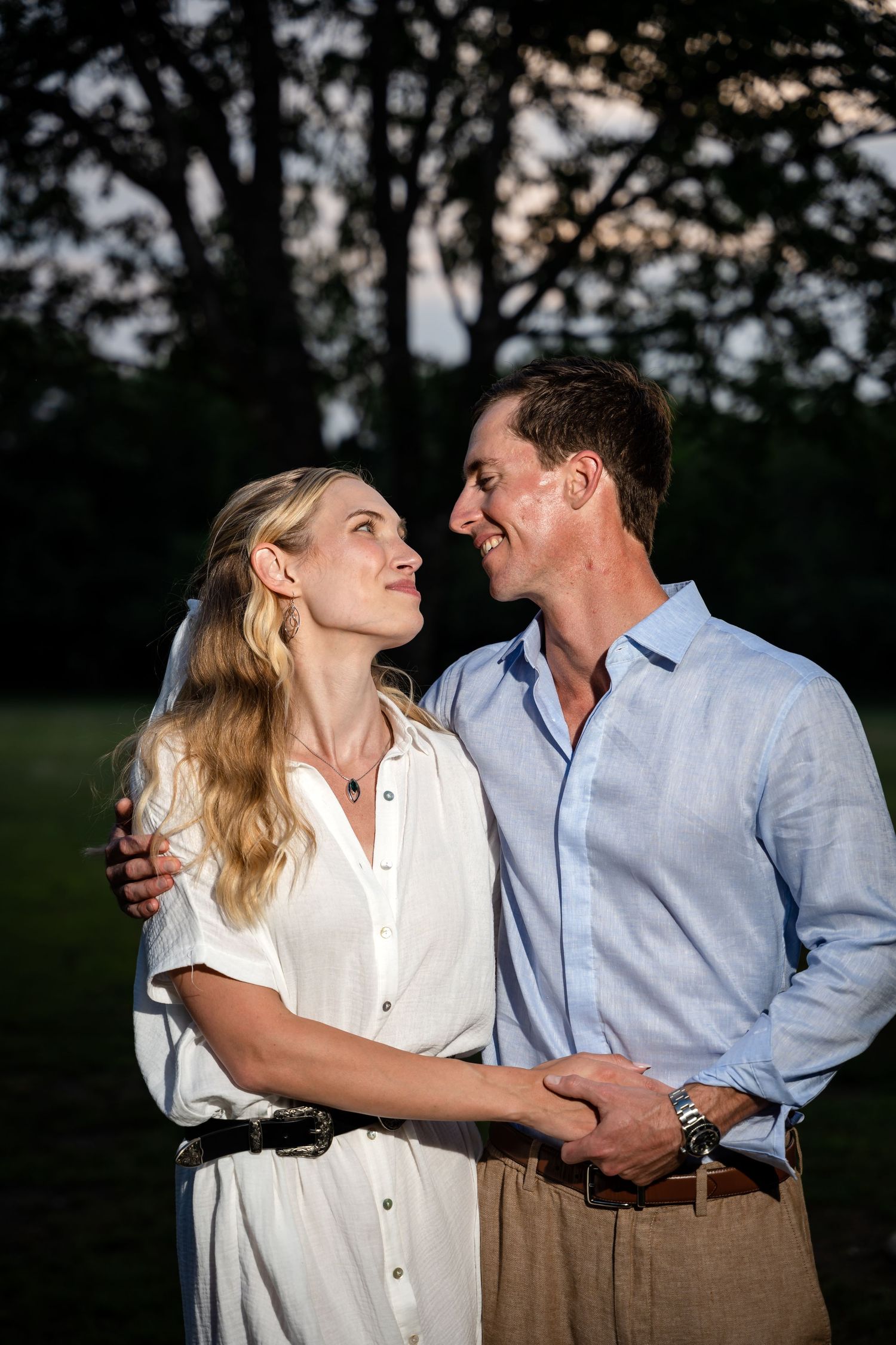 Romantic couple shares an intimate moment at sunset in a park setting.