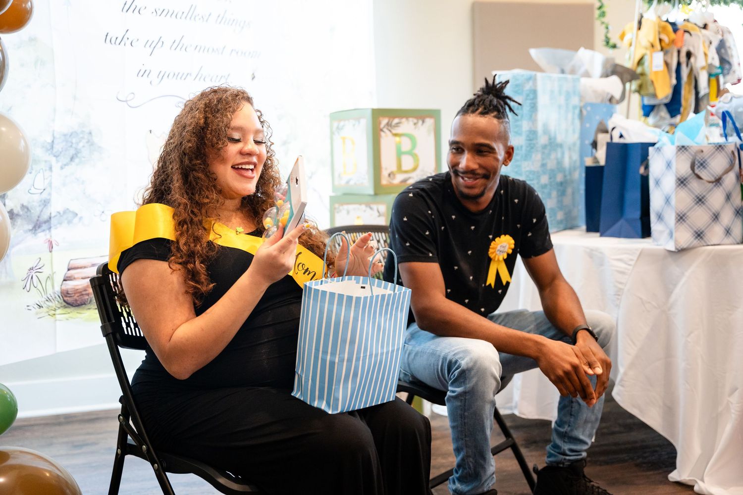 A joyful baby shower celebration with guests opening gifts surrounded by blue and white decorations.