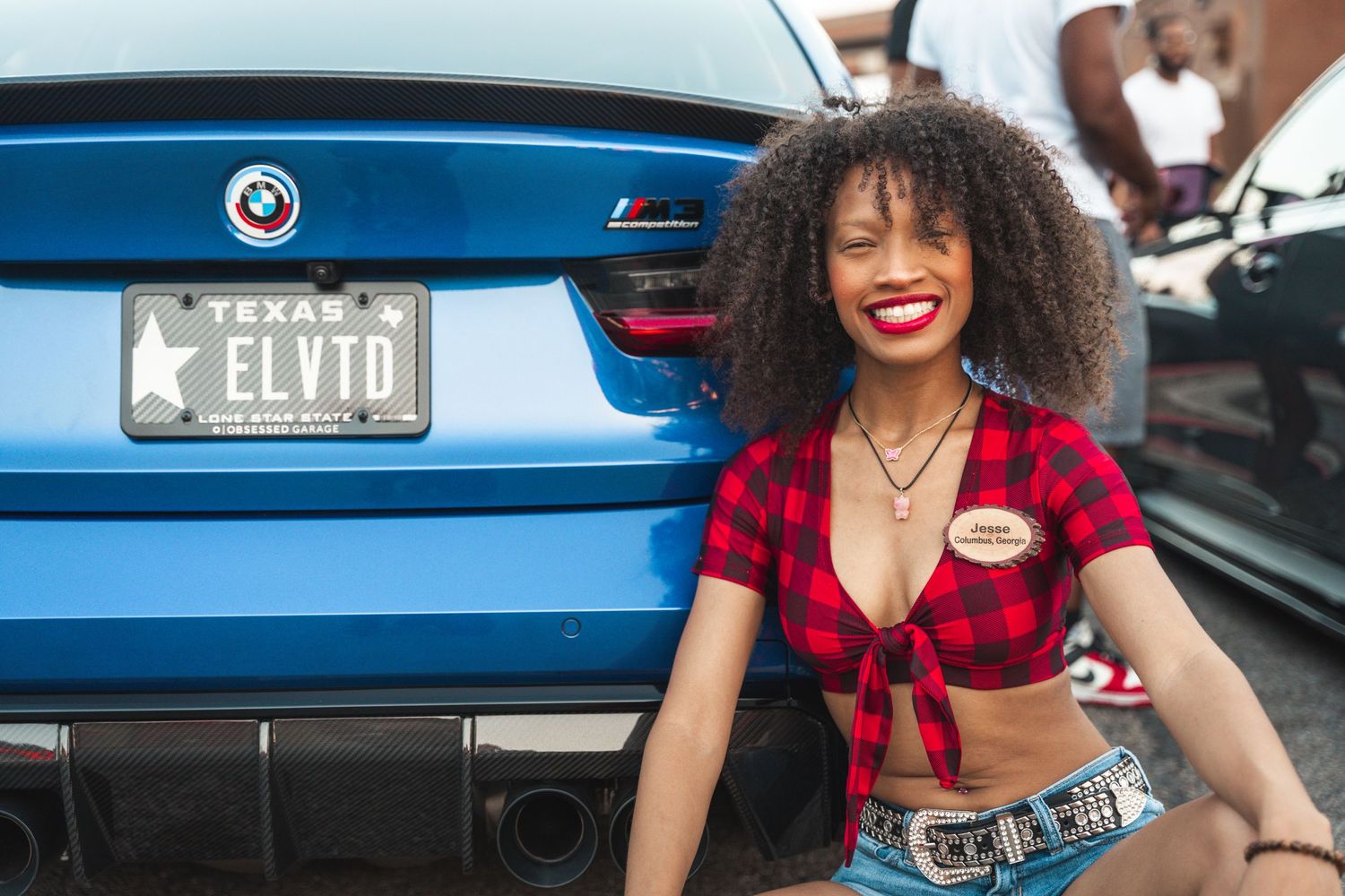 Rear view of blue BMW with custom license plate at car meet.