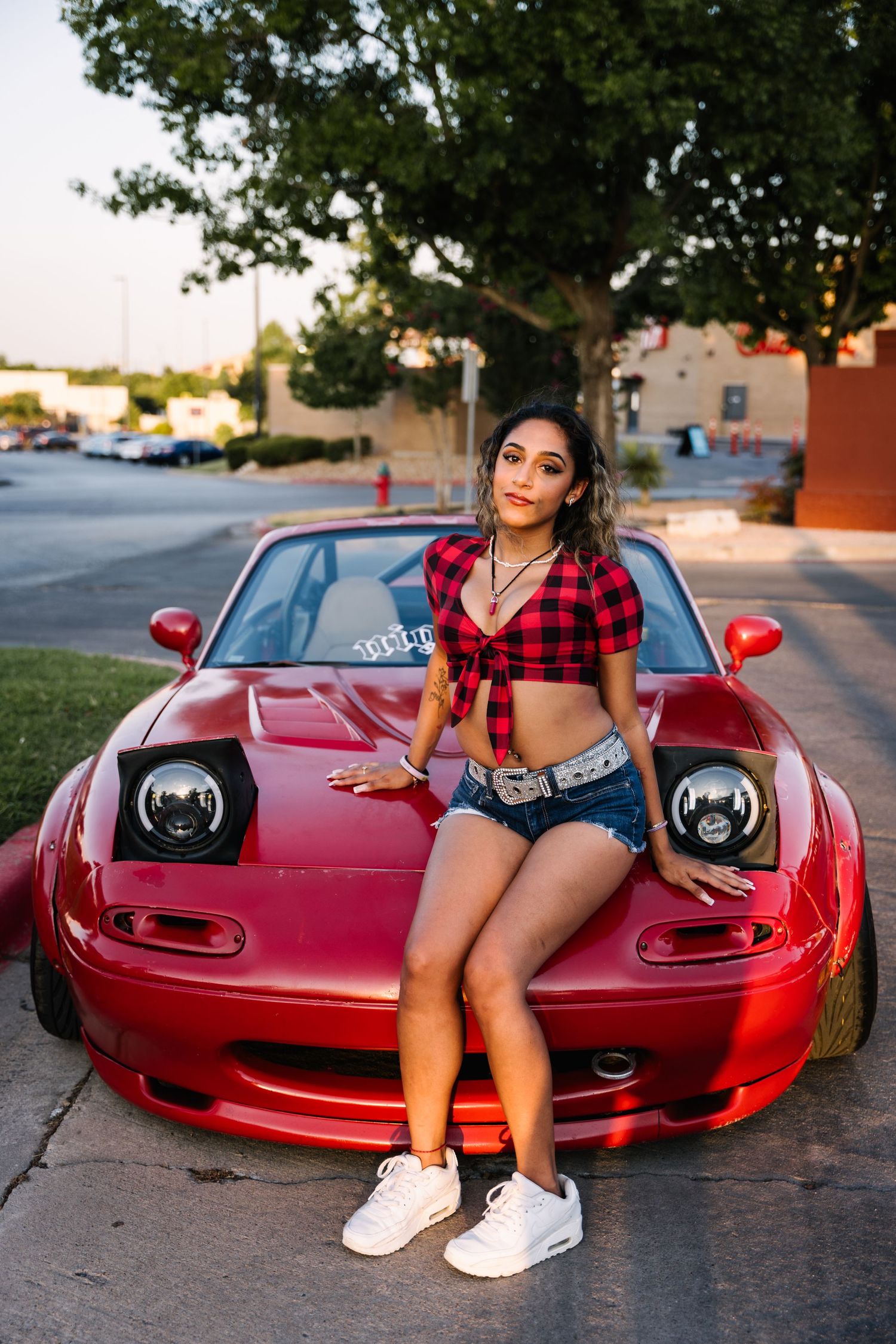 Custom red Mazda Miata parked outdoors at a car meet.