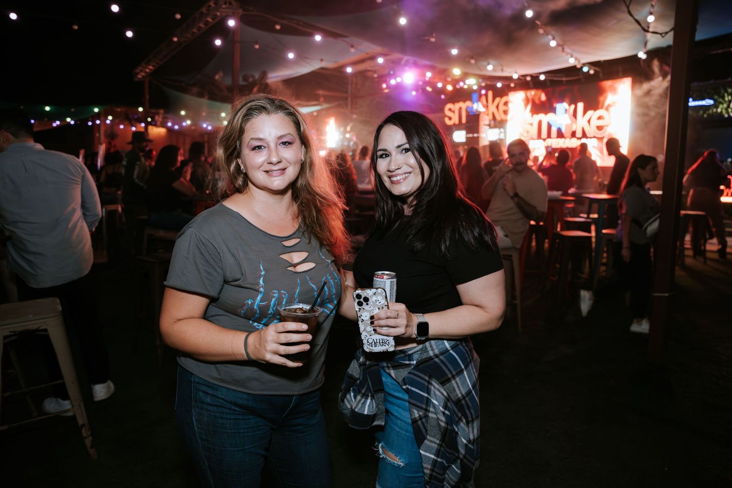 Patrons enjoying drinks inside a dimly lit bar with neon lighting.