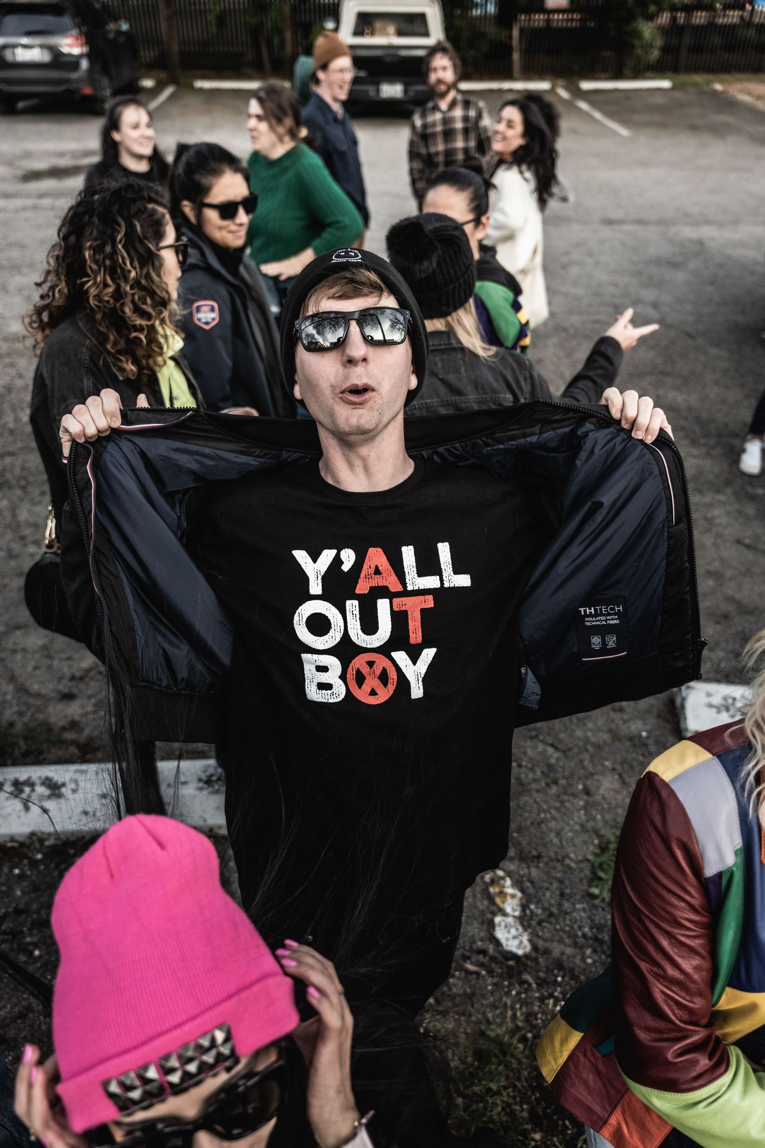 Excited crowd at outdoor event wearing casual clothing with person in black 