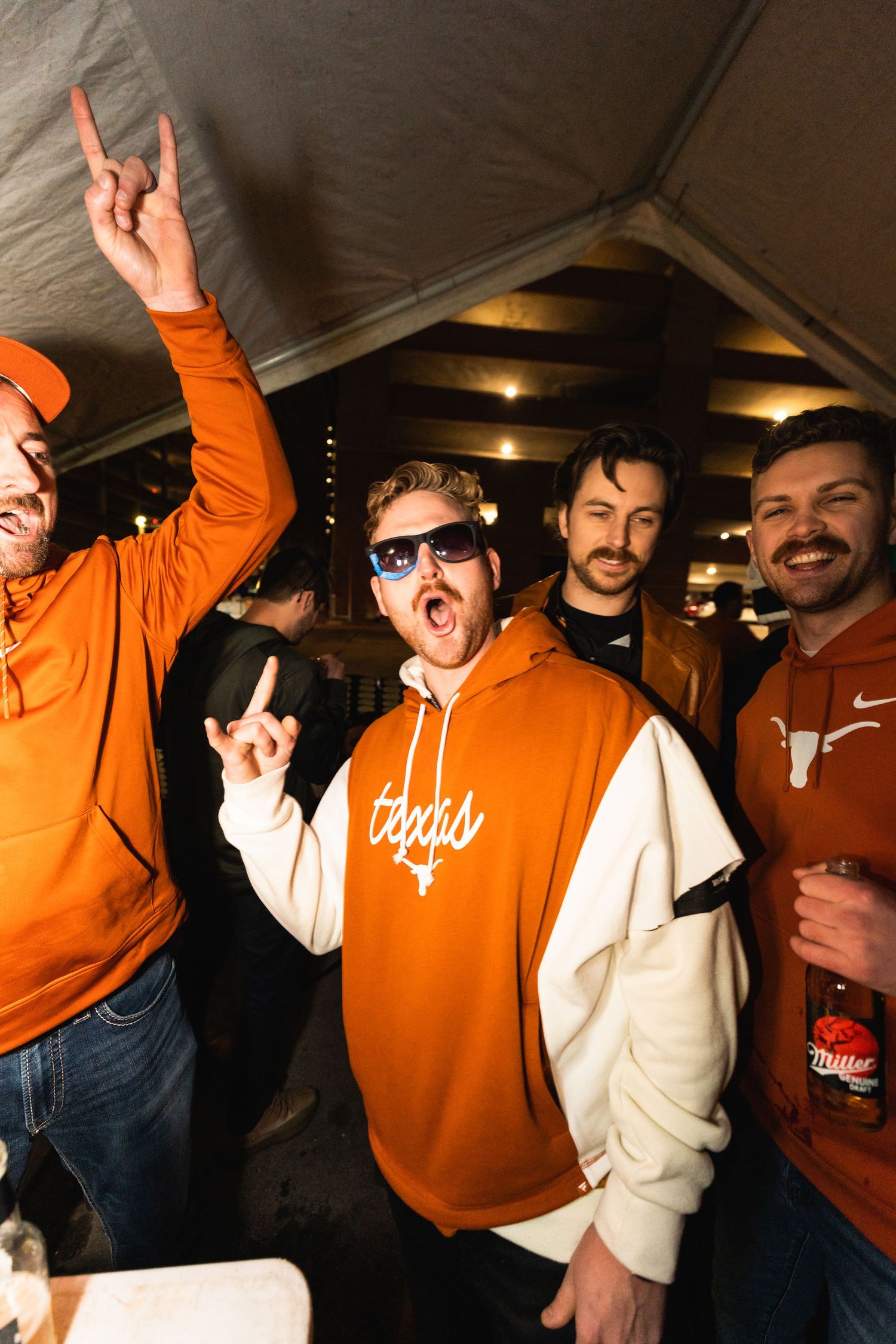 Group of friends in orange Texas-themed hoodies celebrating together at night event.