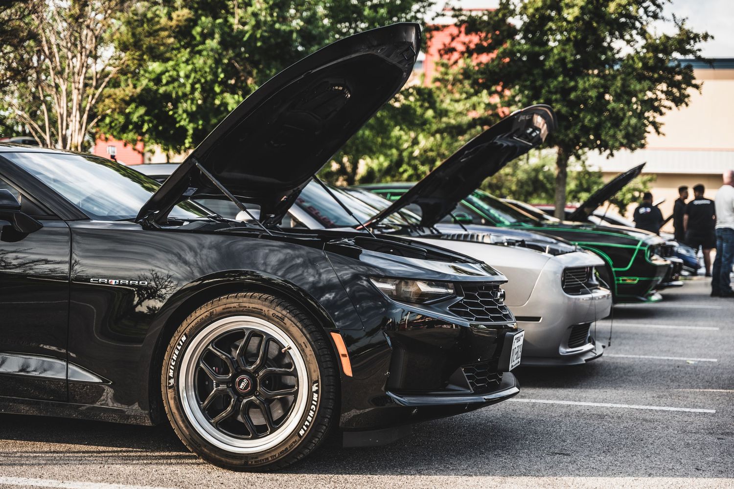 Modified black sports car with open hood displaying engine at car show.