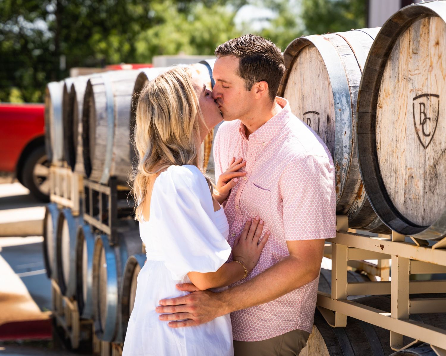 A romantic moment between a couple in front of wine barrels at a winery.