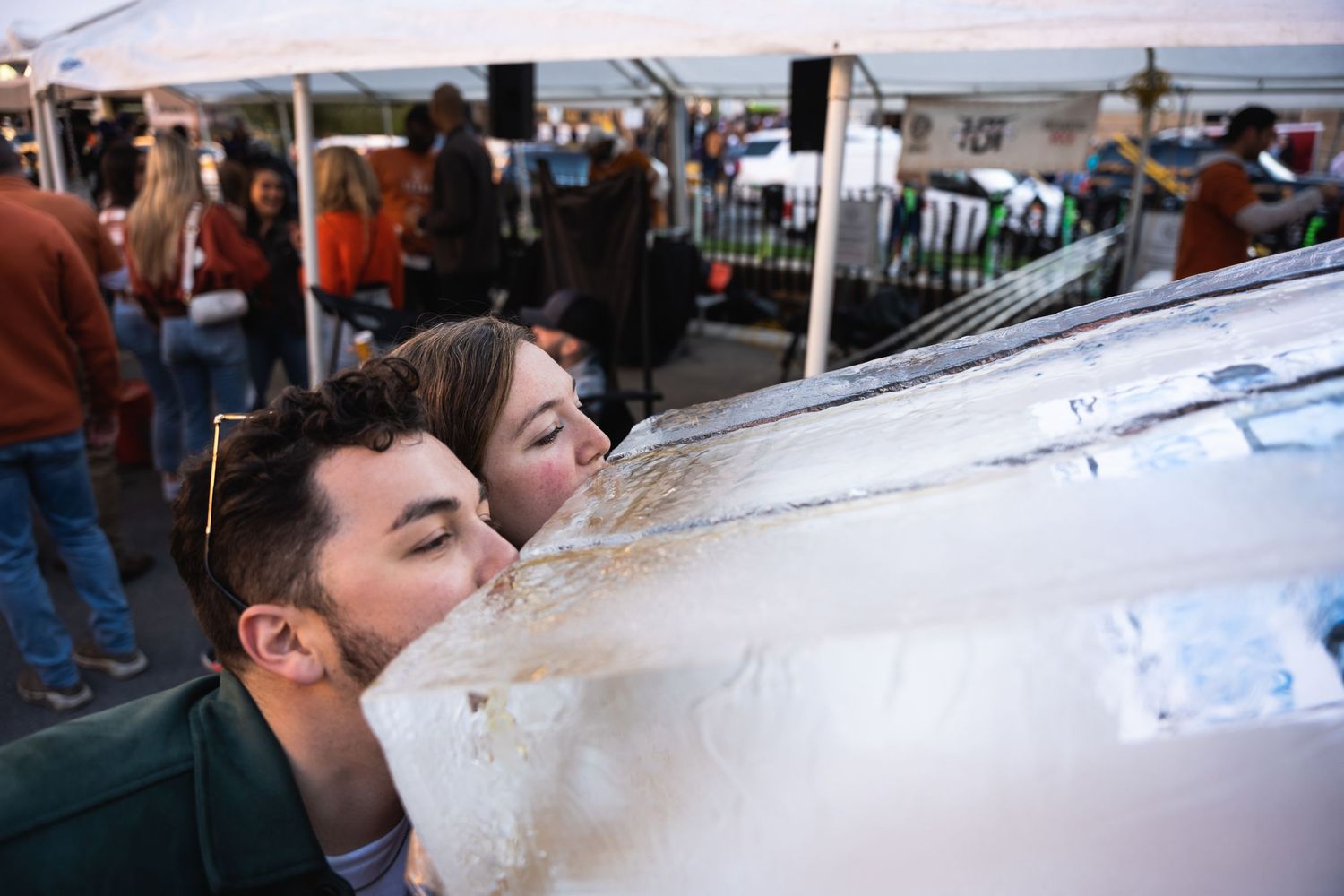 Someone drinks from an ice luge at a crowded outdoor party.