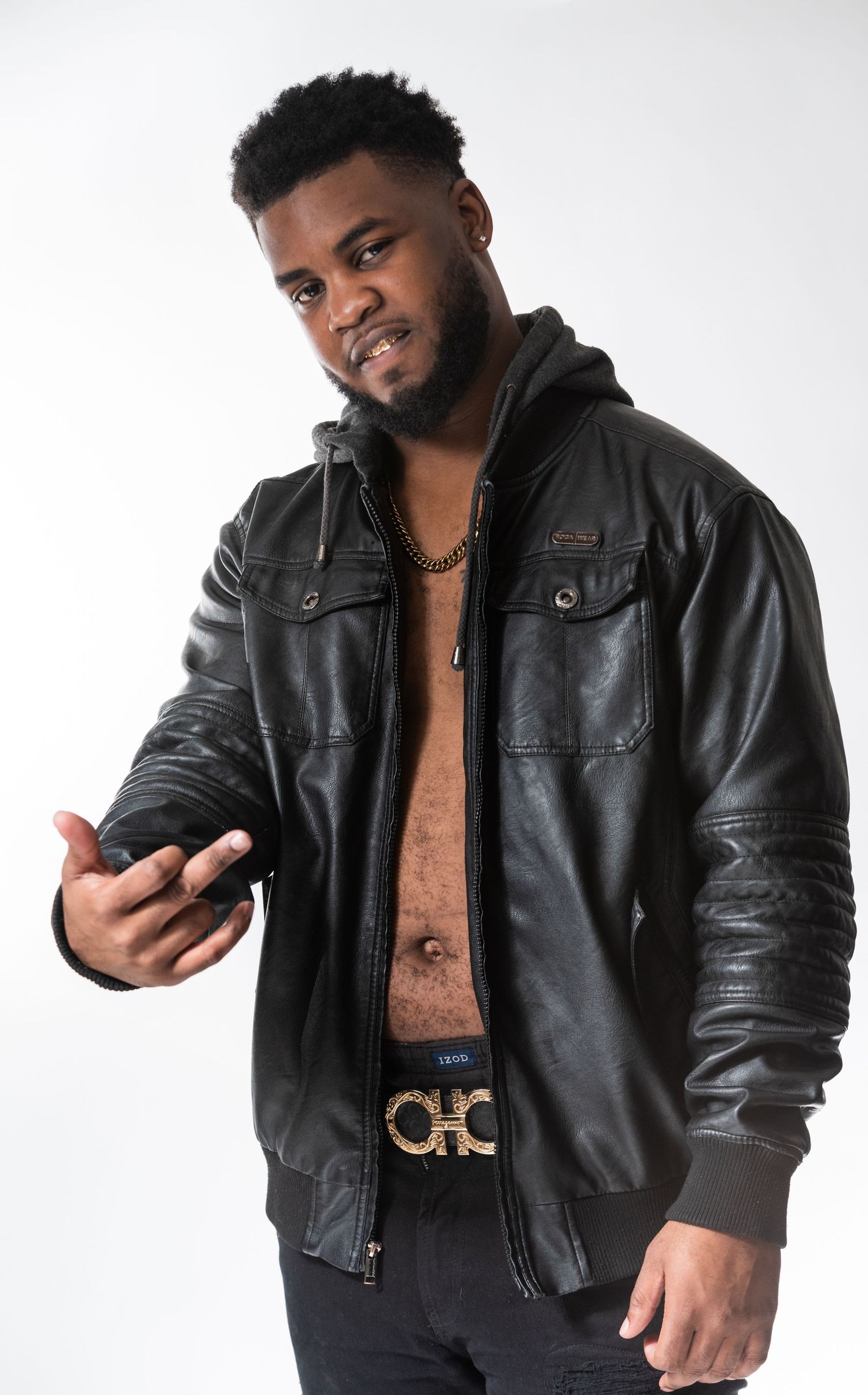 Athletic build model in open leather jacket and designer belt poses against white studio backdrop.