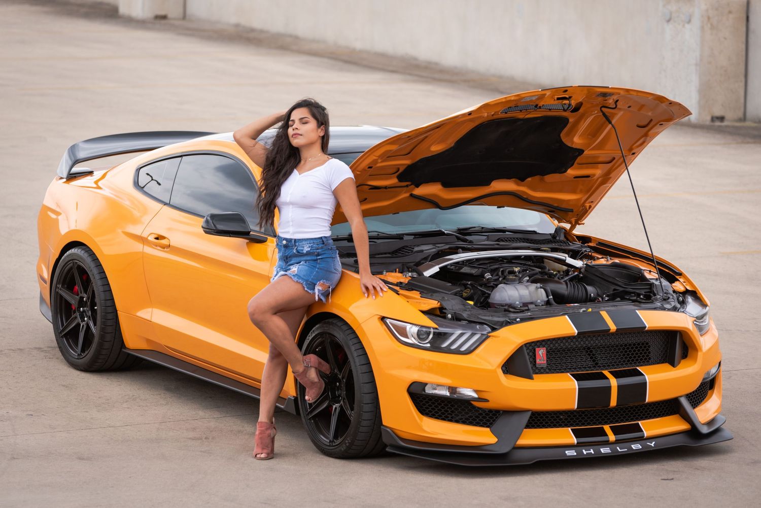 Orange Mustang Shelby GT350 with hood open displaying its powerful engine.