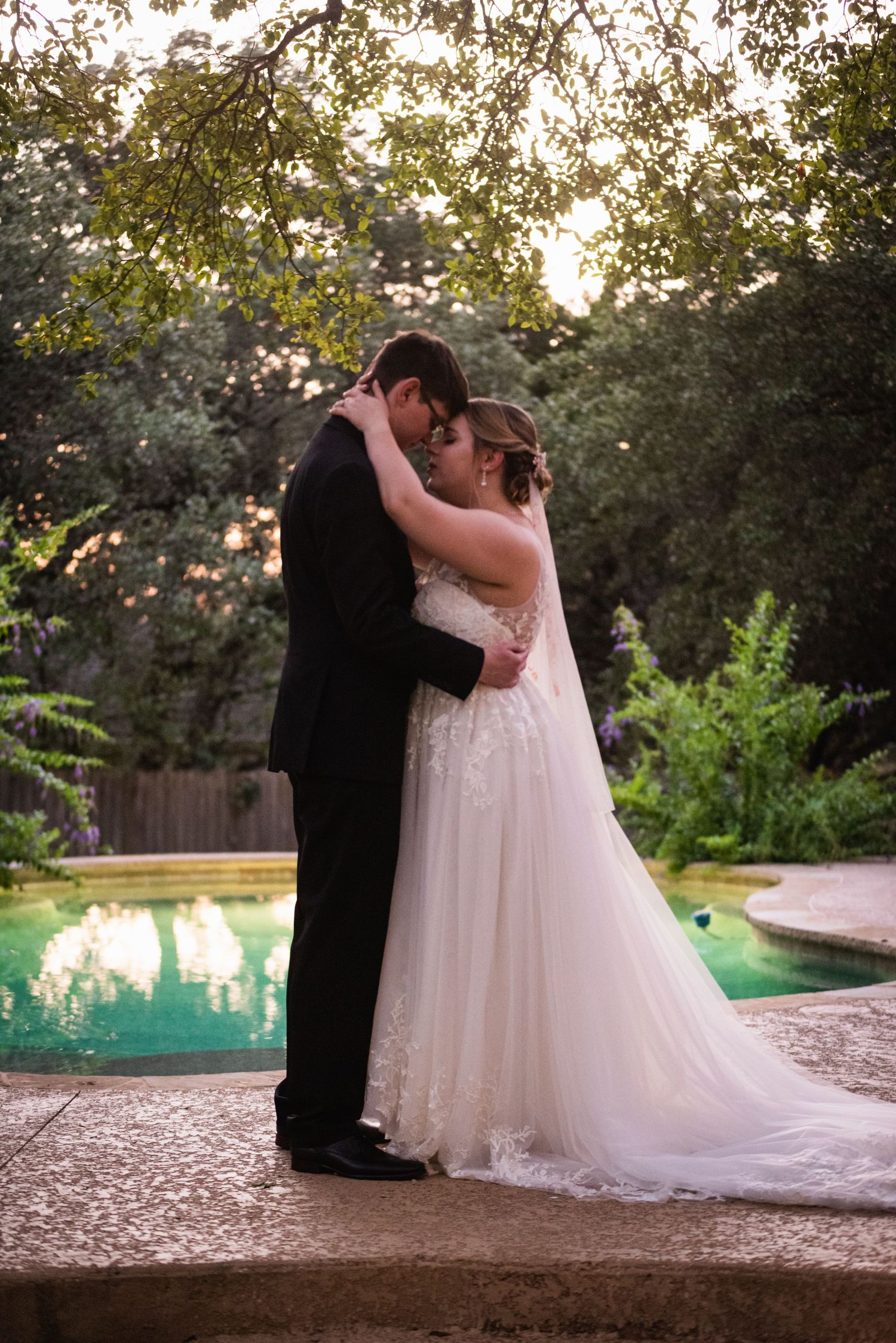 A romantic sunset wedding portrait by a pool with a couple in an intimate embrace.