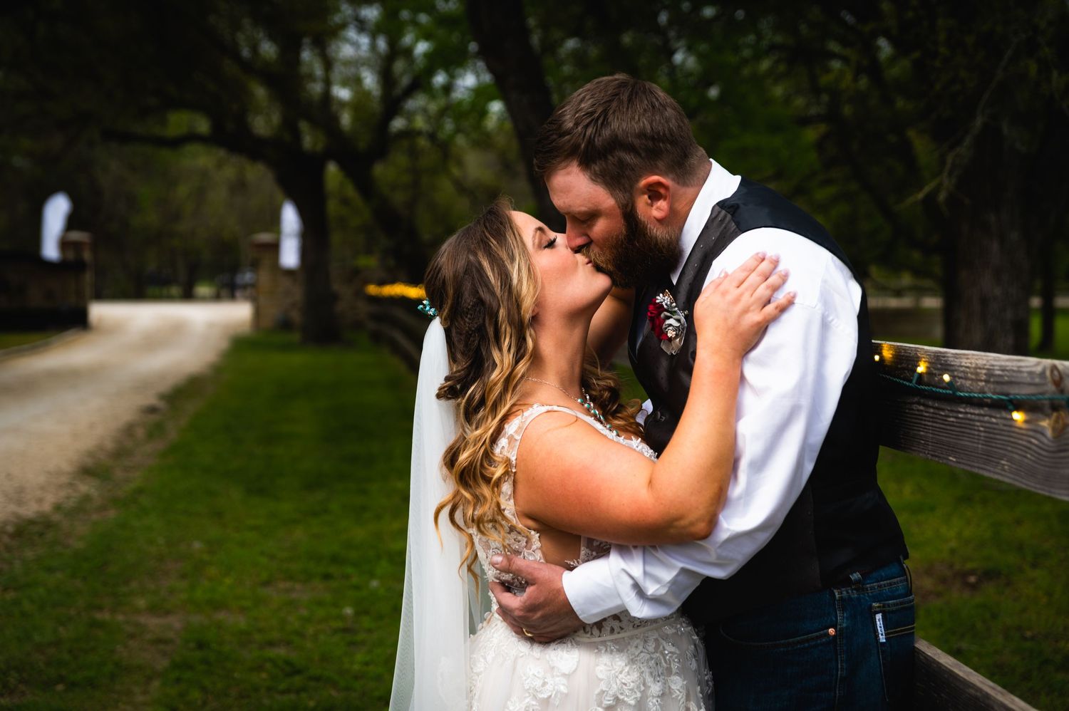 Romantic wedding kiss captured in an outdoor garden setting.