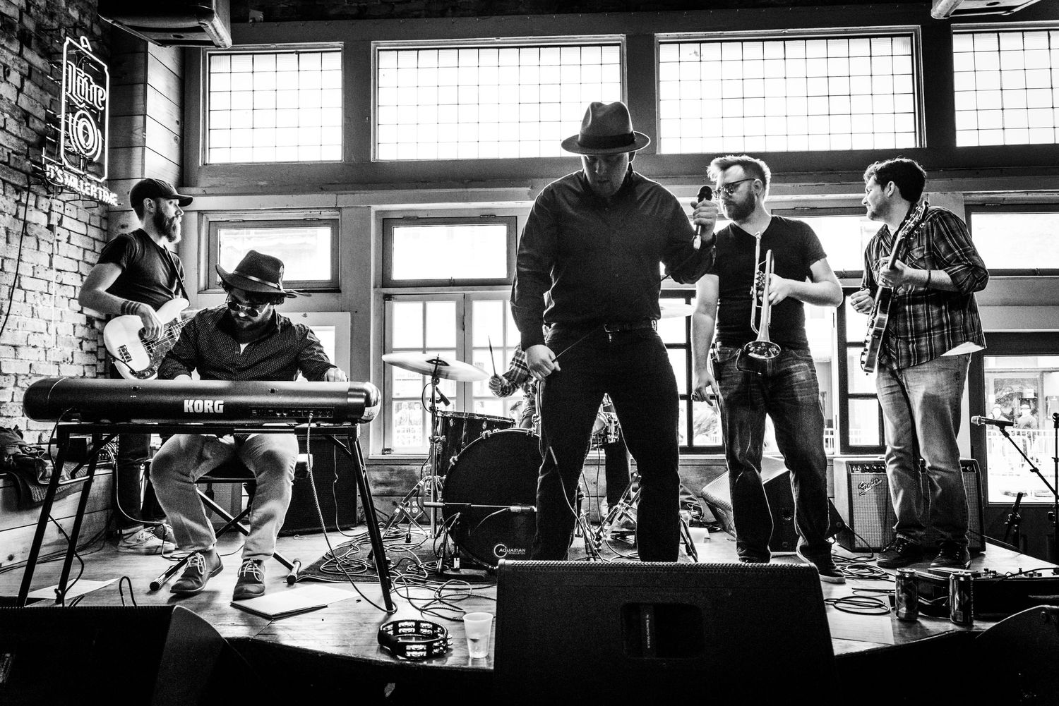 Wide shot of band members performing on stage with instruments in black and white photography.