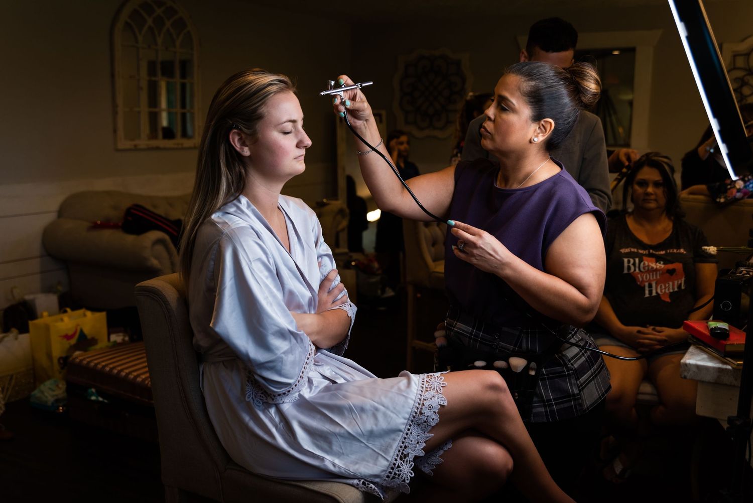 A person applying makeup to someone seated in a chair.