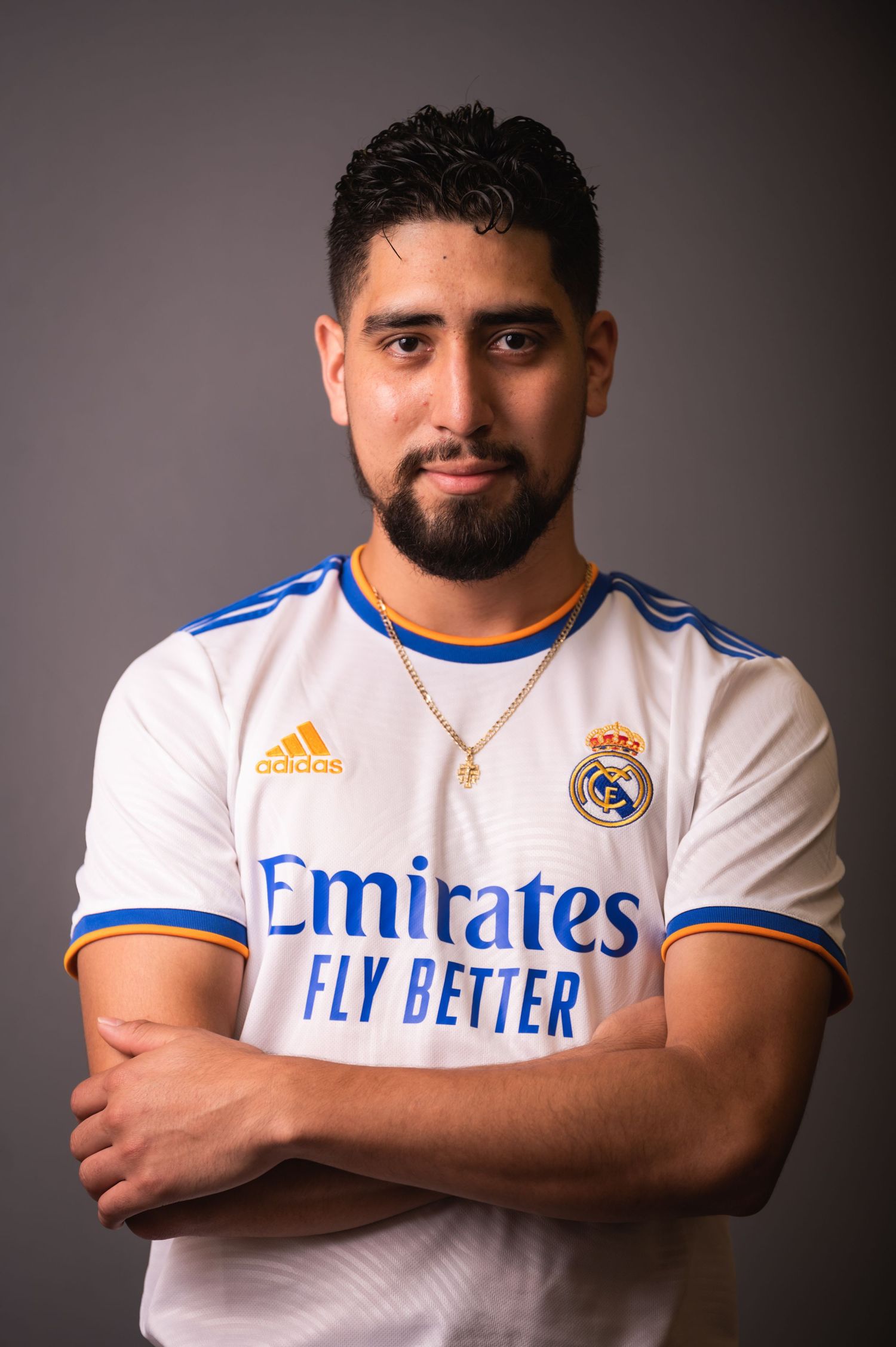 Athletic figure in Real Madrid jersey poses against grey background.
