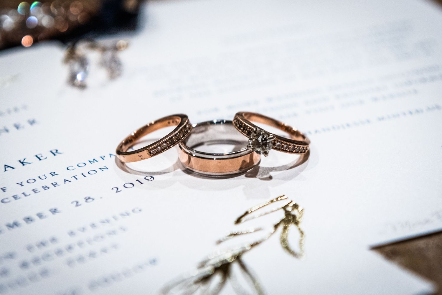 Wedding rings displayed on white paper with rose gold and silver bands.
