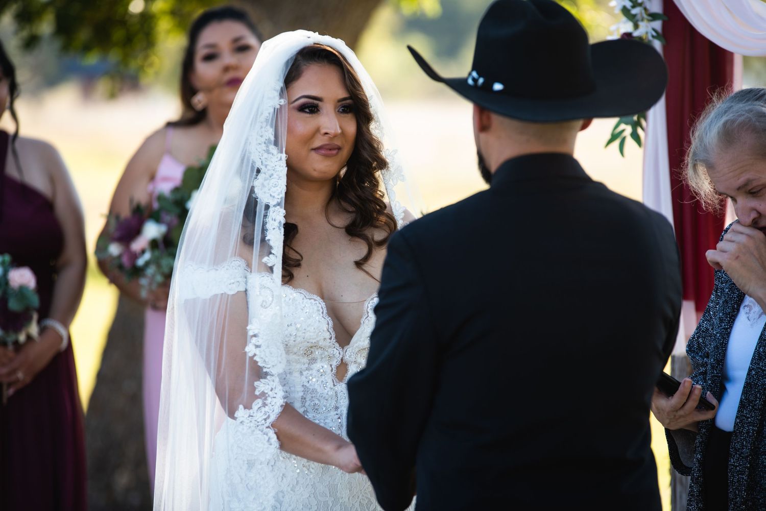 Outdoor wedding ceremony with white and floral decorations under a wooden arch.
