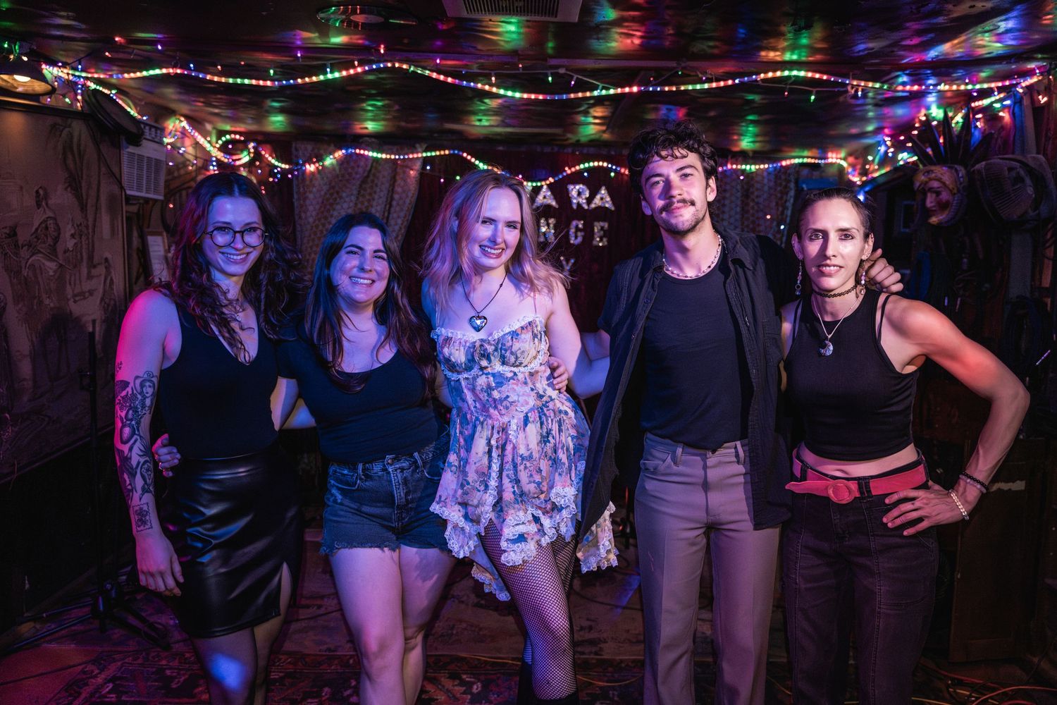 A group of people enjoying a night out at a dimly lit bar or club with colorful lighting in the background.