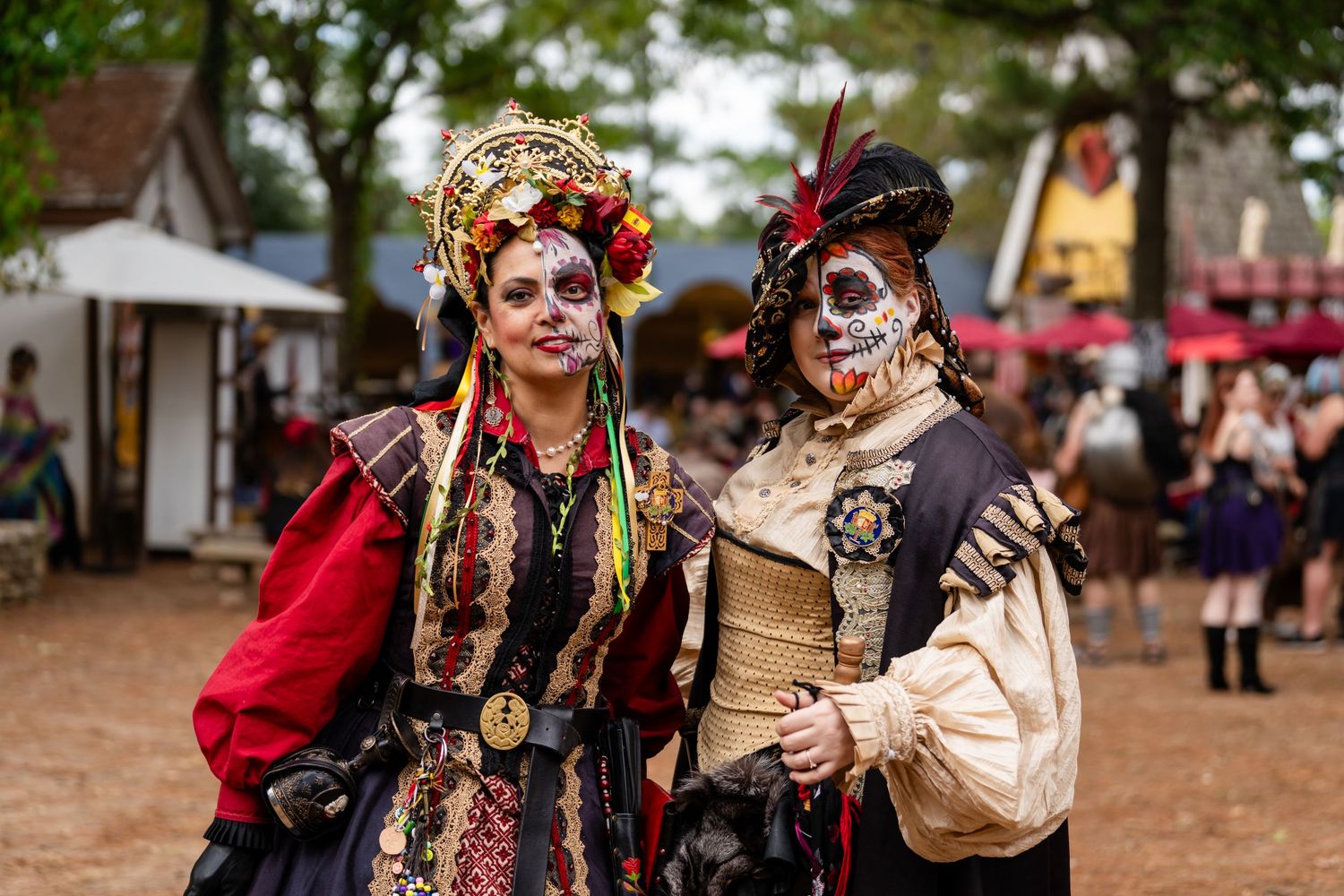 Performers in elaborate Day of the Dead costumes and face paint pose together at an outdoor festival celebration.