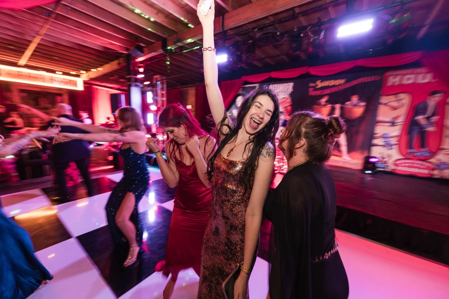 People dancing and socializing in a nightclub with vibrant pink and purple lighting creating a lively atmosphere.