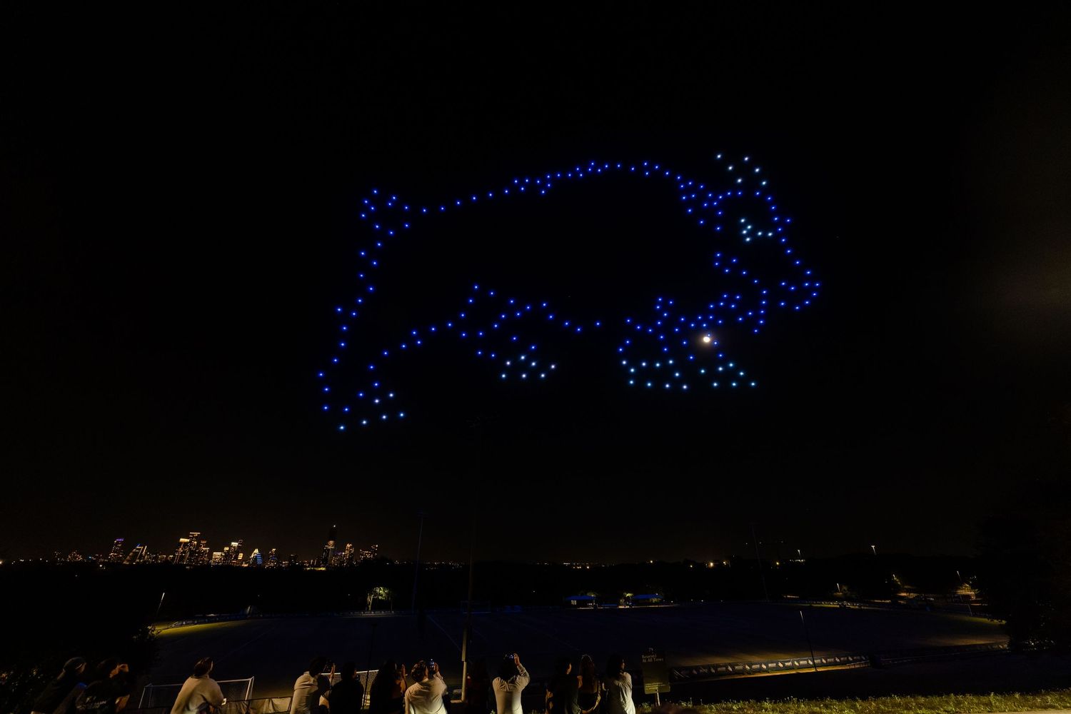 Illuminated drone light show forms mesmerizing patterns against the dark night sky.