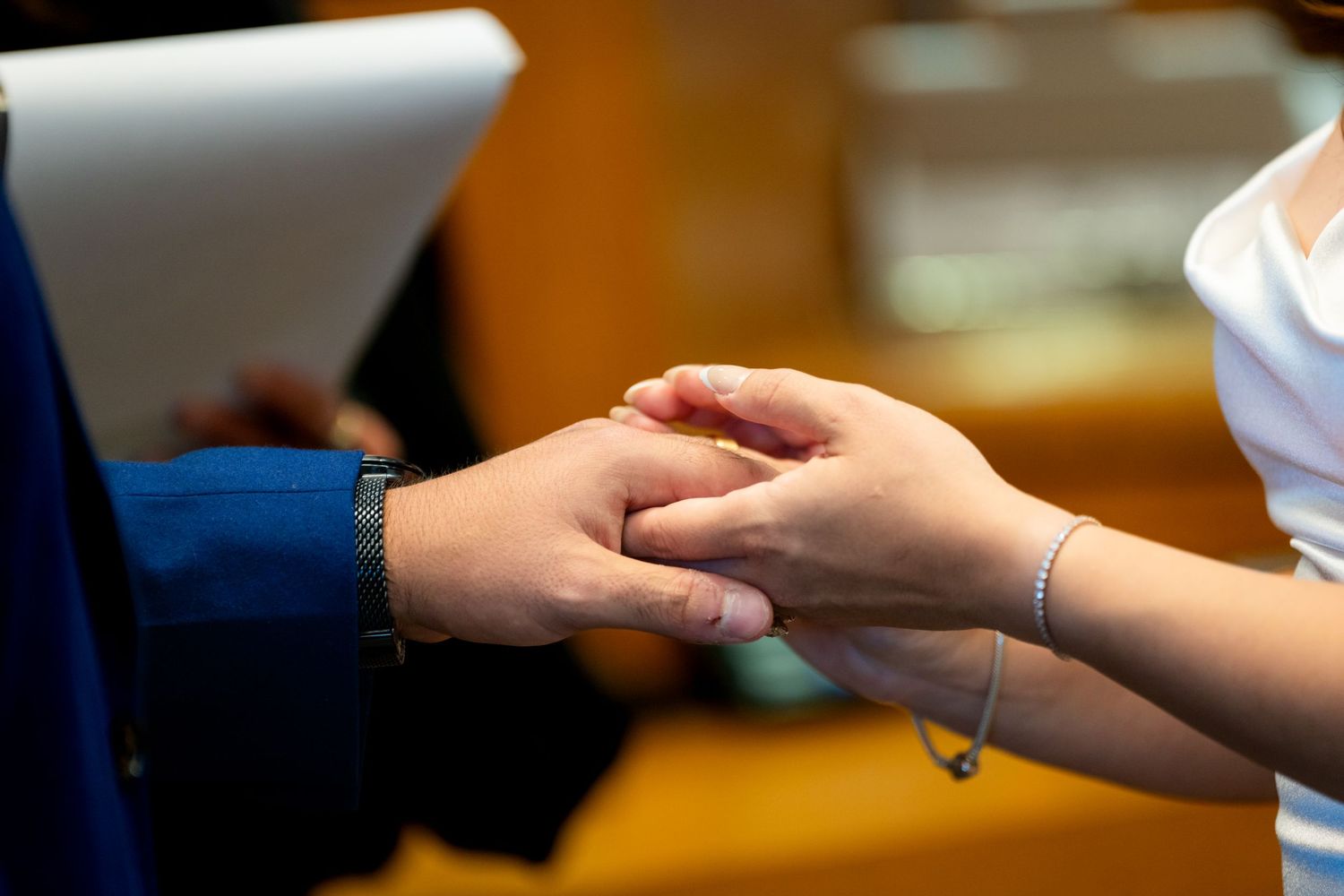 Close-up view of hands passing a credit card during a payment transaction at a point of sale terminal.