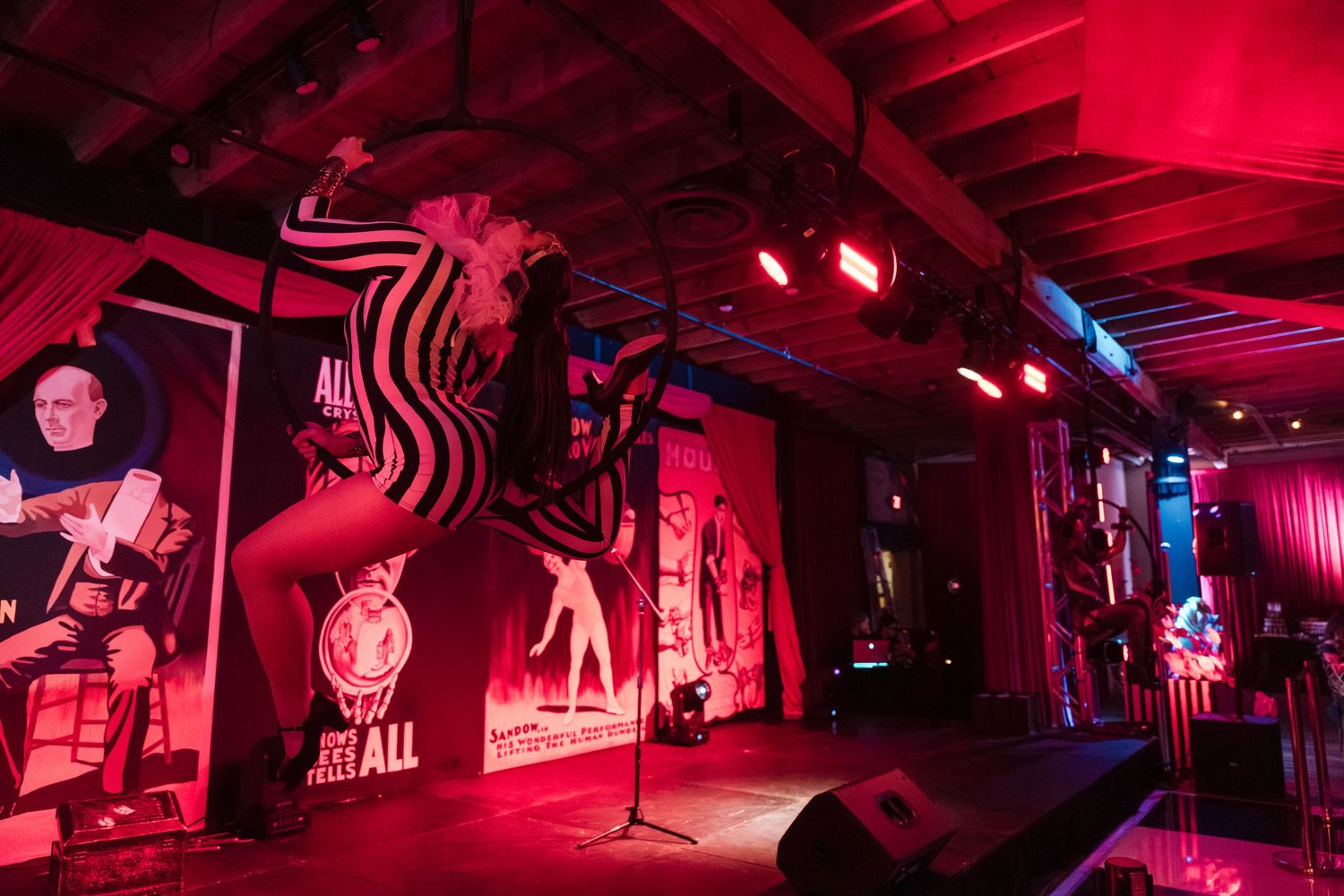 Nightclub interior with red lighting and dark silhouettes creates a moody, atmospheric ambiance.