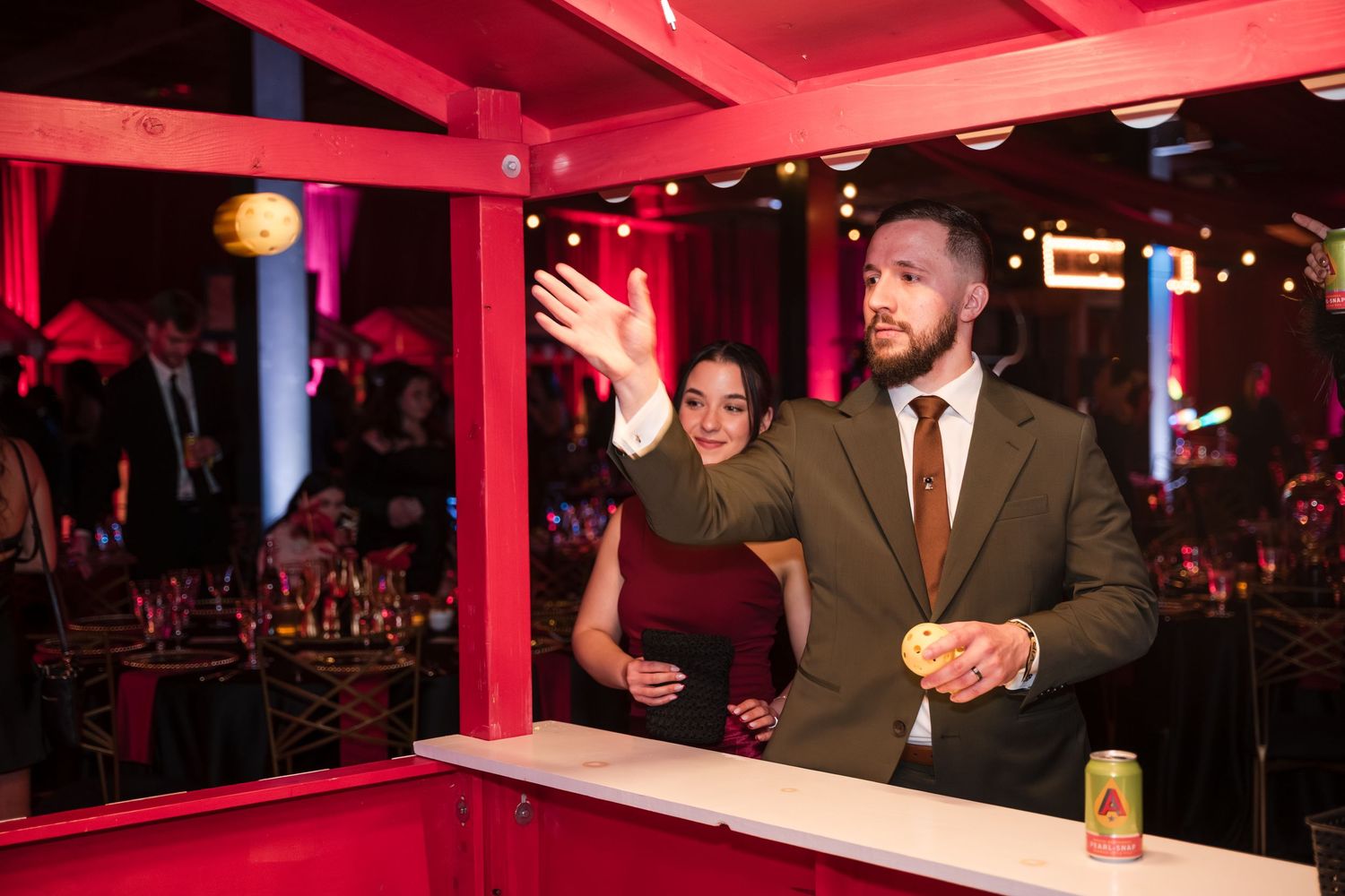 Nightclub interior with red lighting and people socializing at a bar during an evening event.