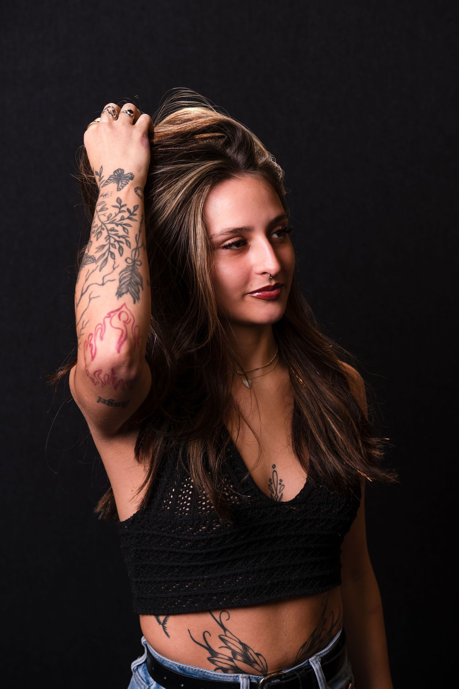 A dramatic series of photos showing a person with tattoos in dark clothing against a black background.