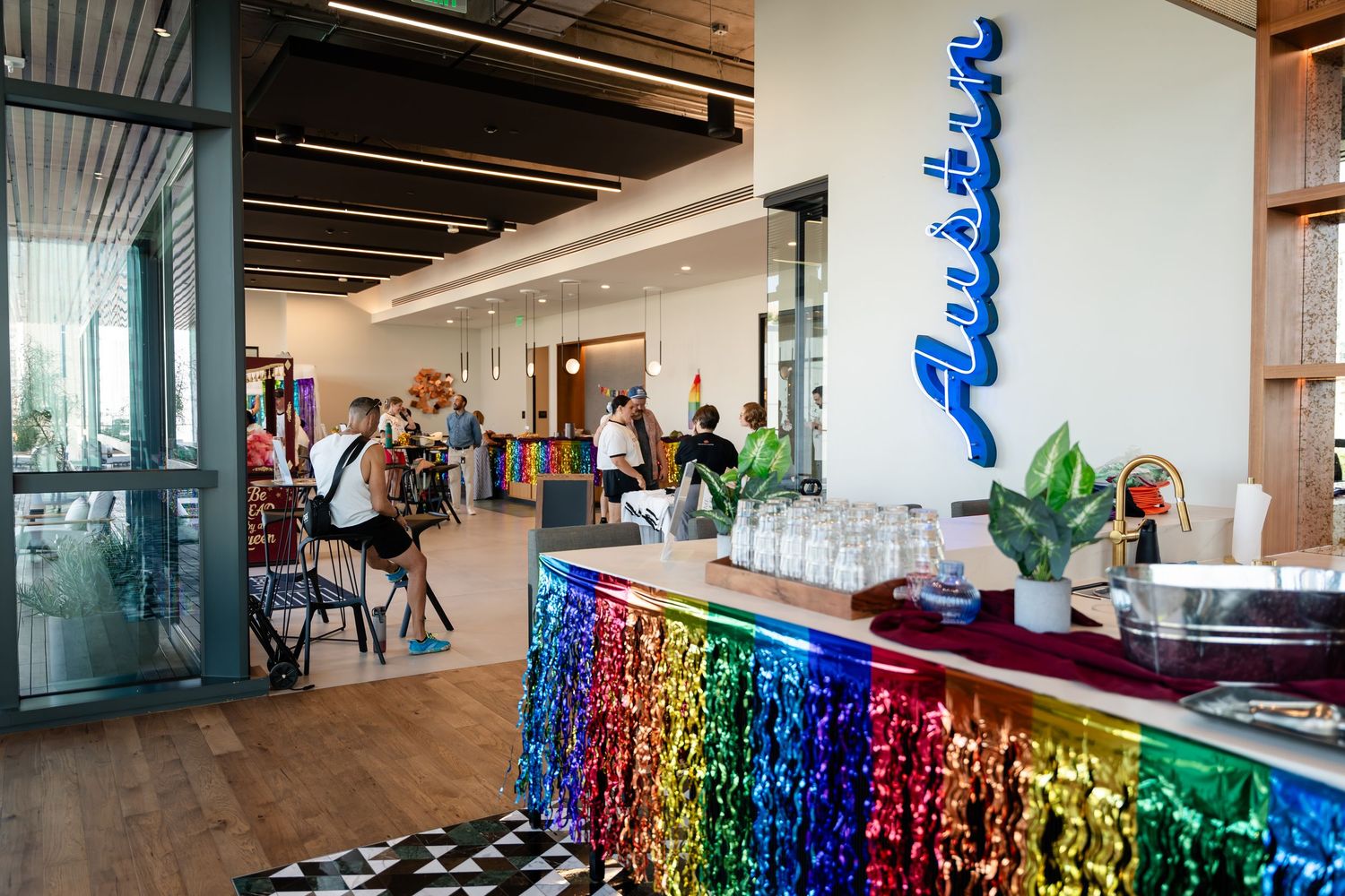 Colorful rainbow-skirted bar counter in a modern Austin office space with neon Austin sign and open lounge area.