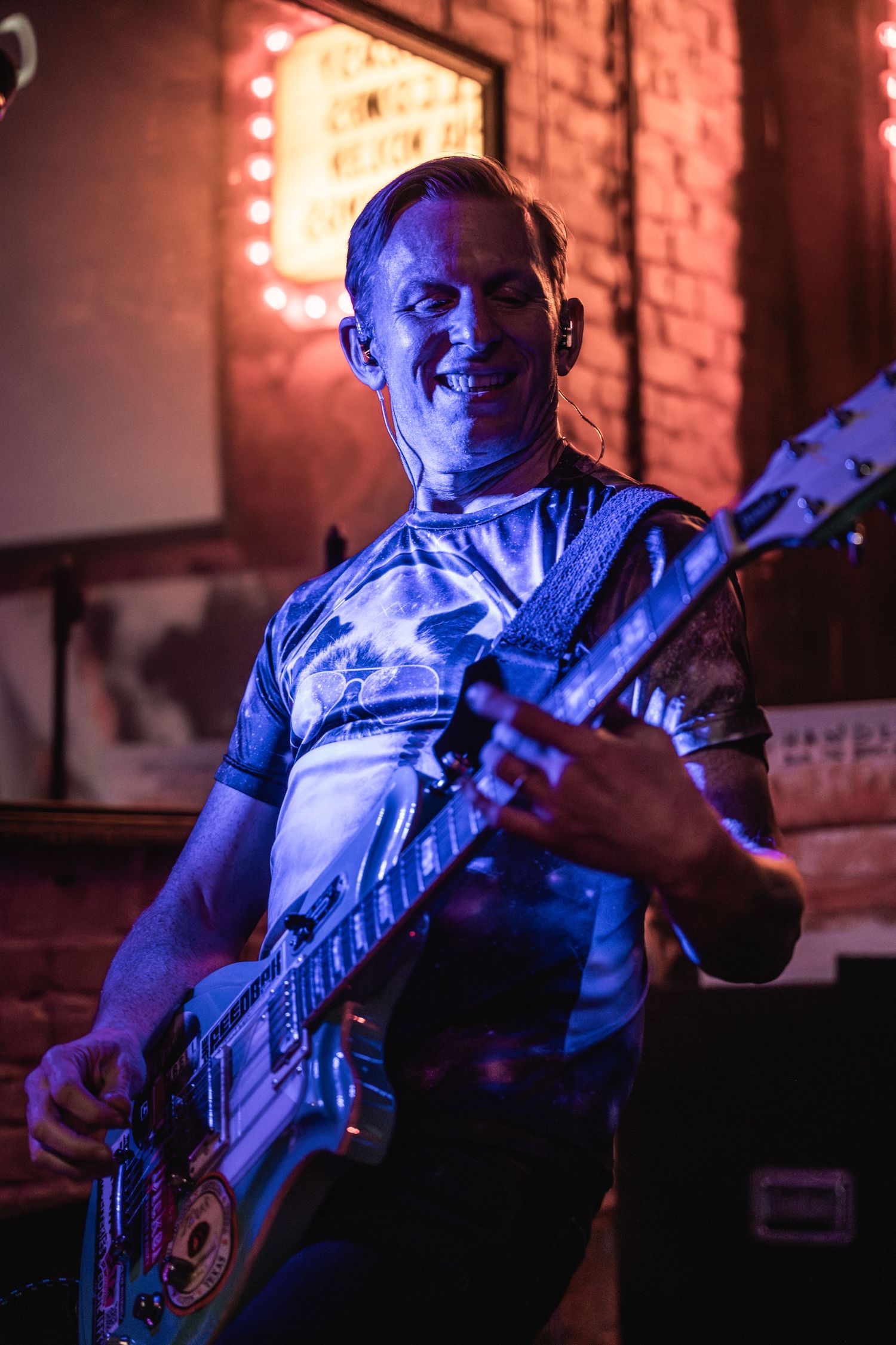 Bass guitarist performing on stage with blue and red lighting effects.