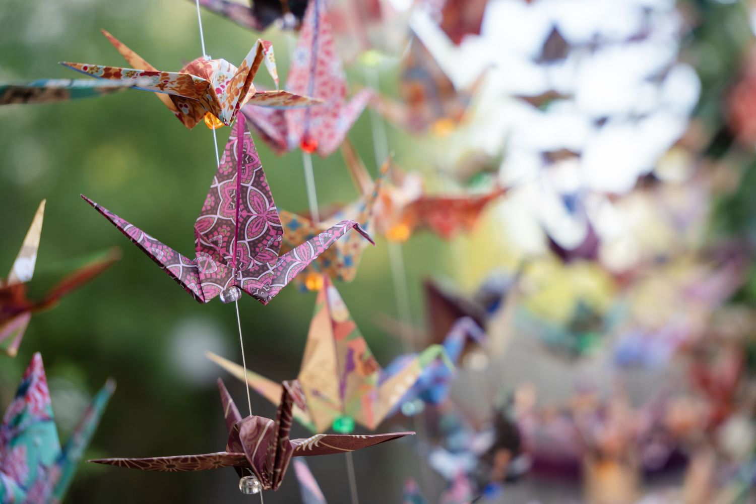 Delicate paper origami cranes in pink and purple tones hanging as decorative elements.